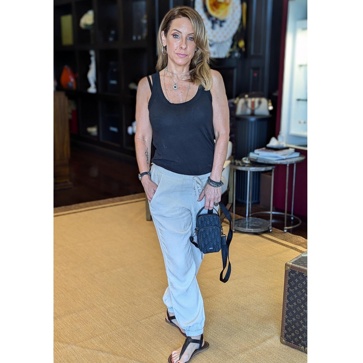 This stylish crossbody is crafted of oblique Christian Dior oblique canvas in black. The bag features a leather top handle, an optional adjustable shoulder strap, a front zipper pocket with a dark silver Dior logo, and dark silver hardware. The