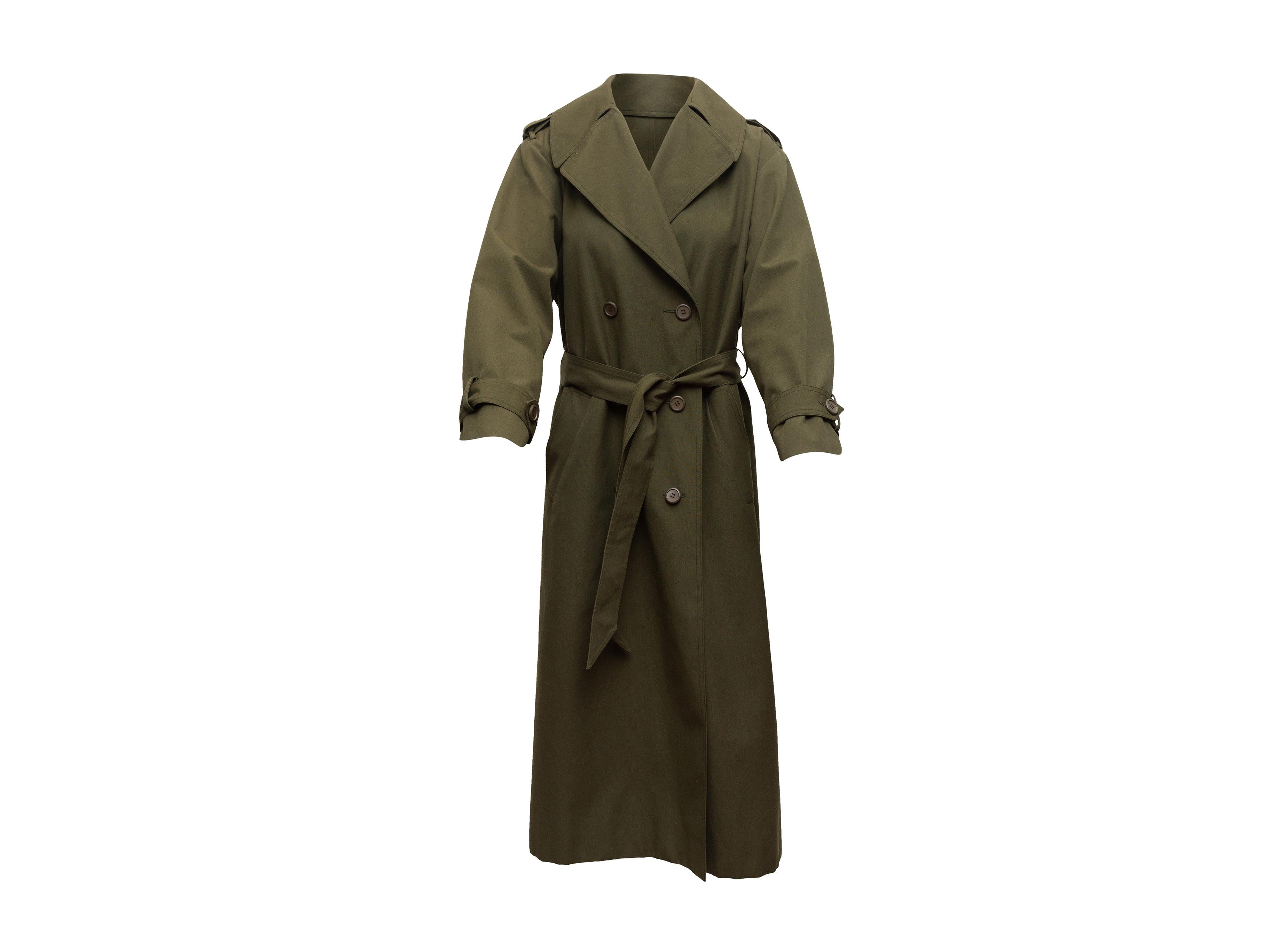 Product details: Vintage olive long double-breasted trench coat by Christian Dior. Notched lapel. Dual hip pockets. Sash tie at waist. Button closures at front. 40