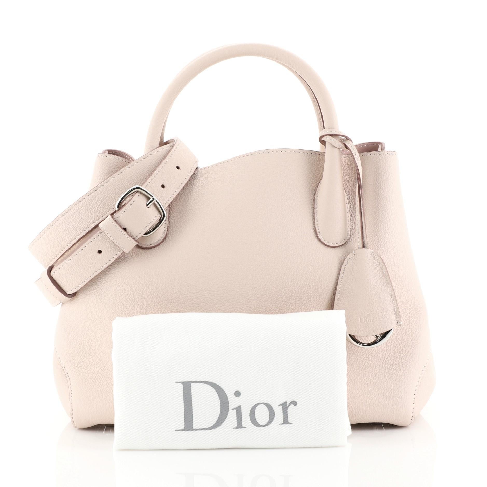 This Christian Dior Open Bar Bag Leather Small, crafted in pink leather, features dual rolled handles, protective base studs, and silver-tone hardware. Its wide top with belted side closure opens to a pink leather interior with snap and slip