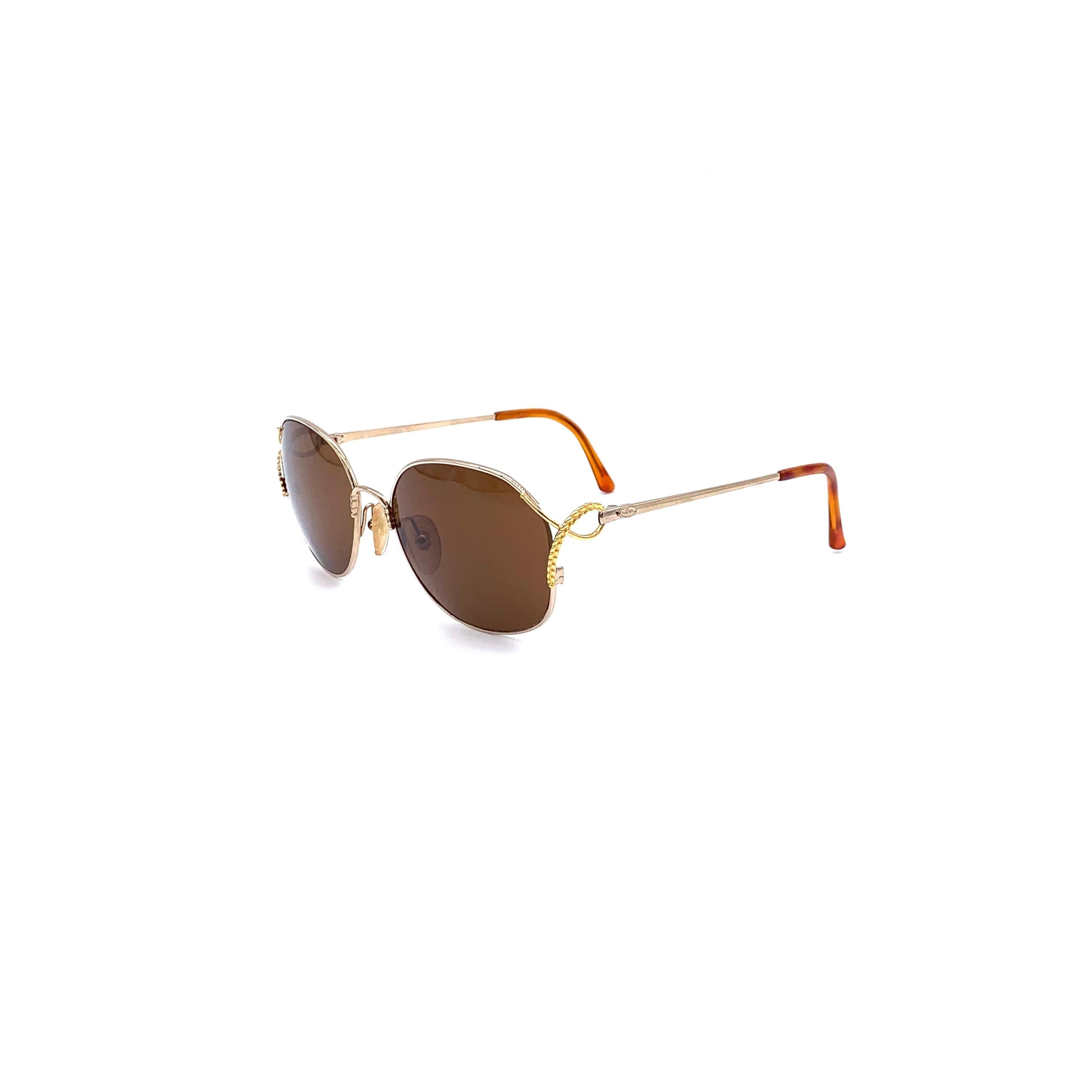 These classic Christian Dior sunglasses are constructed with a gold metal frame and Optyl lenses in a brown shade. A distinctive leaf pattern detail accentuates the sides of the frame, providing 80s appeal with modern protection from the sun.
