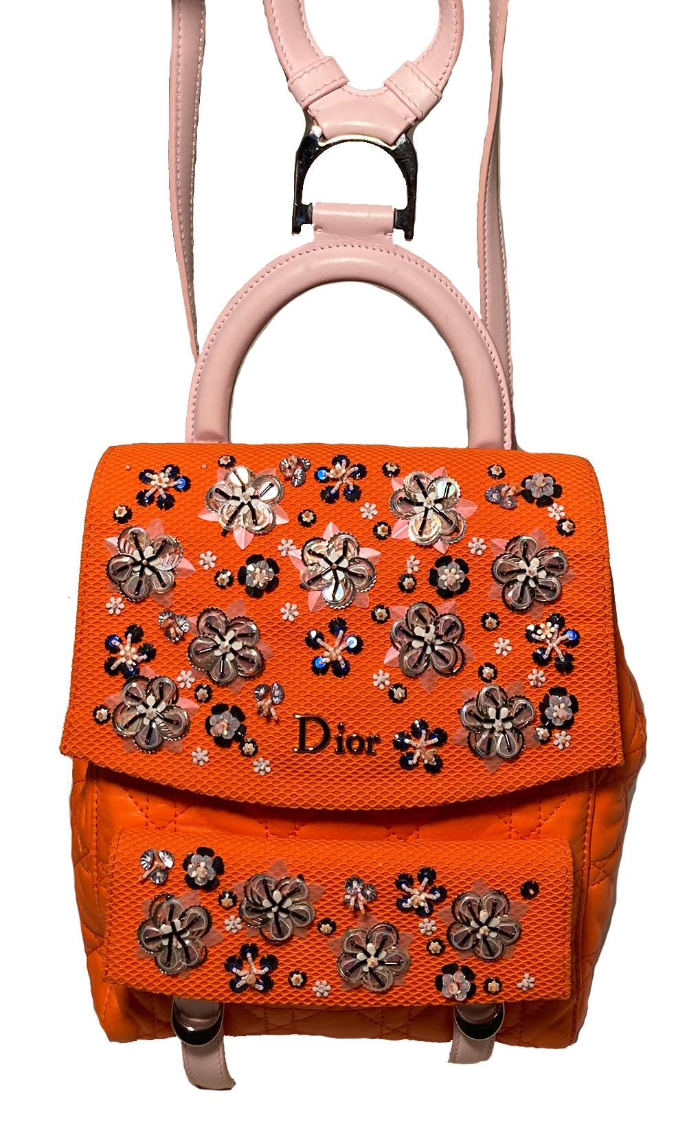Christian Dior Orange Stardust Backpack in NWOT condition. Orange cannage quilted leather exterior trimmed with pale pink leather shoulder straps, silver hardware and delicate floral beaded embroidery throughout the front side. Front double buckle