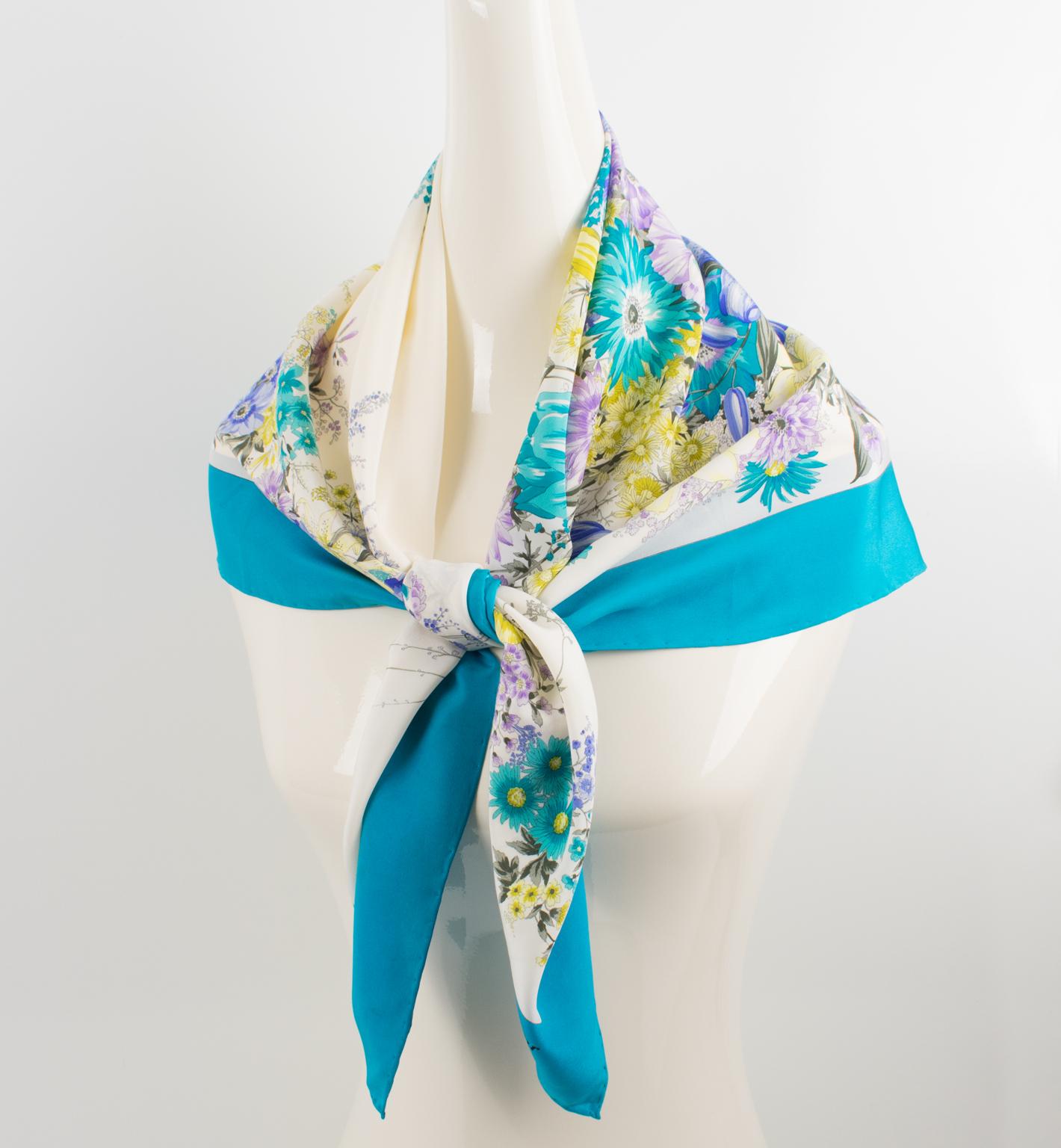 This elegant silk scarf by Christian Dior in blue and lavender colors features a floral design print. The Christian Dior's signature name is in the lower right corner. The combination of colors is bright and vibrant, with cerulean blue, purple