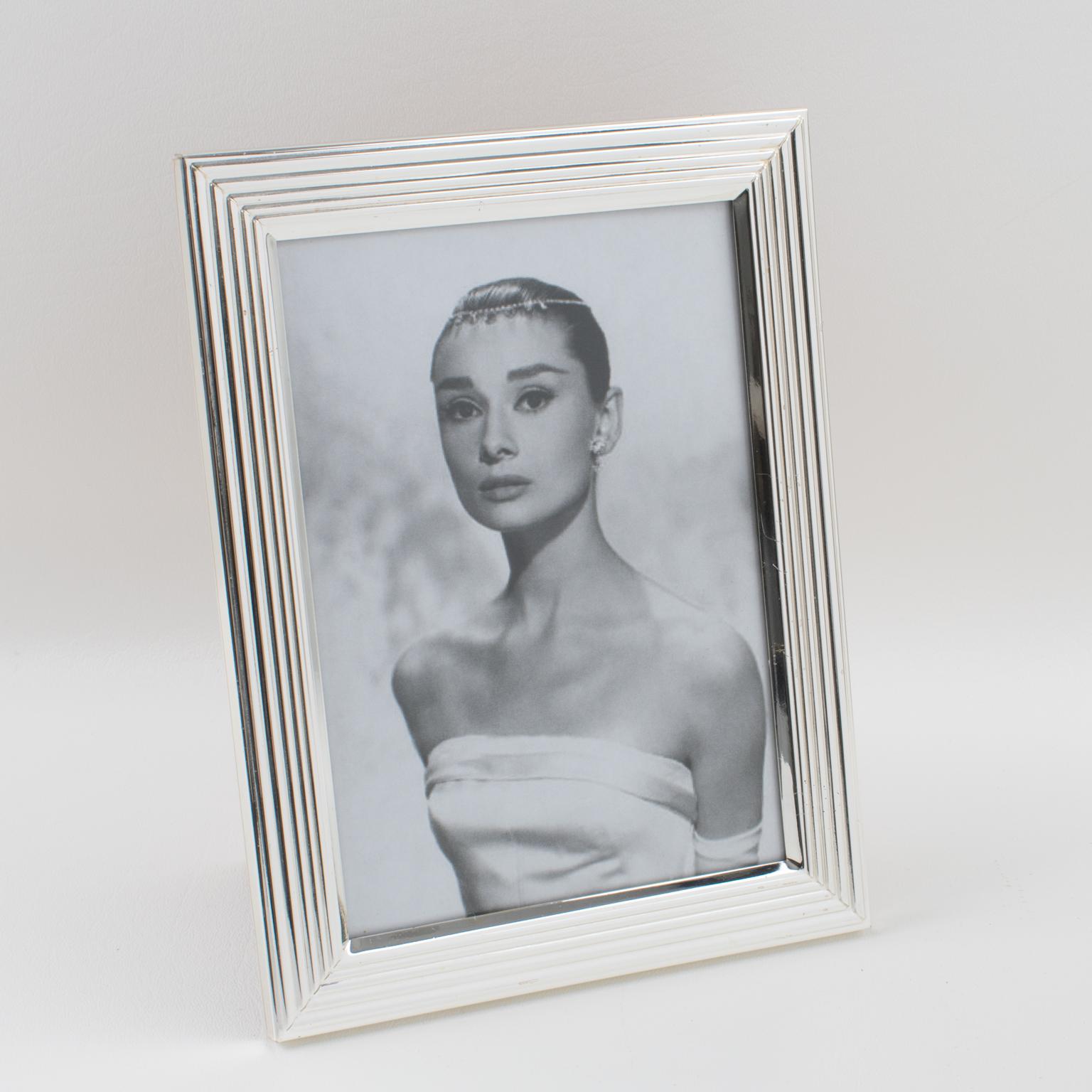 A charming Christian Dior Paris silverplate picture photo frame. Geometric shape with raised striped pattern all around. Back and easel with silky antique rose fabric with the brand logo. Marked on edge 
