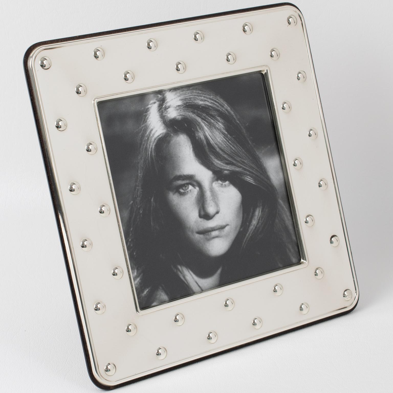 This lovely Christian Dior Paris sterling silver picture photo frame features a square shape with a geometric raised dots pattern all around it. The back and easel are made in high gloss tropical wood. The piece is engraved, on the edge, with the