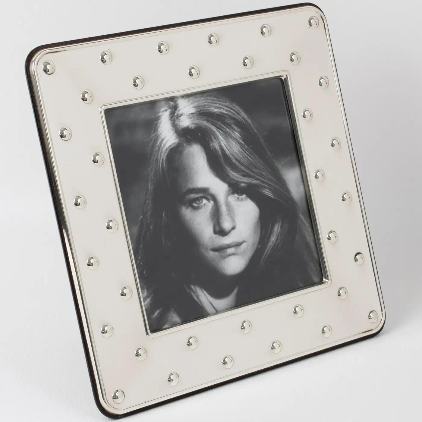 This lovely Christian Dior Paris sterling silver picture photo frame features a square shape with a geometric raised dots pattern. The back and easel are made in high gloss tropical wood. The piece is engraved on the edge with the 