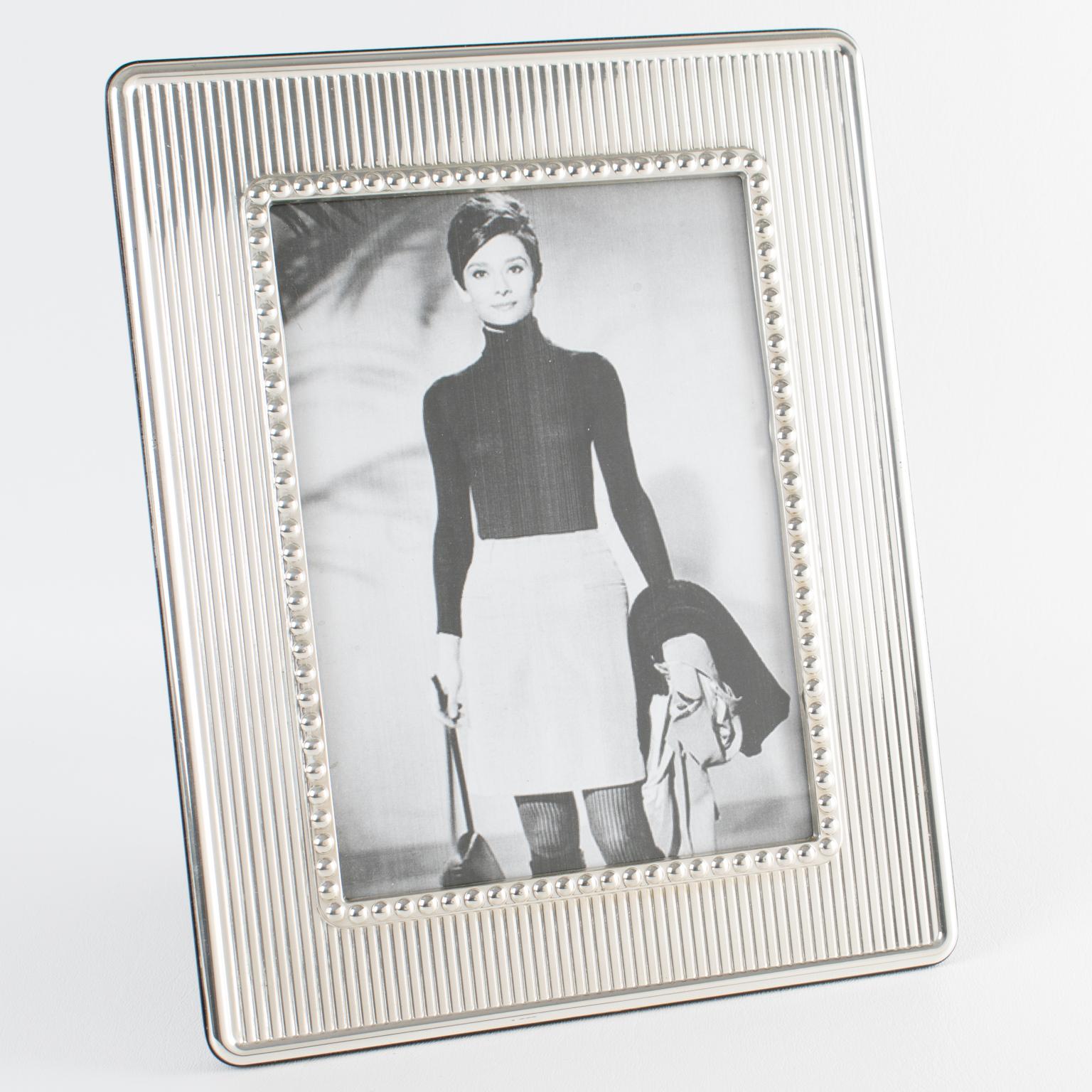 Christian Dior Paris hat diesen eleganten Bilderrahmen aus Sterlingsilber für seine Interior Collection'S entworfen. Der rechteckige Fotorahmen ist rundherum mit geschnitzten Streifen und Perlenmustern verziert. Die Rückseite und die Staffelei sind