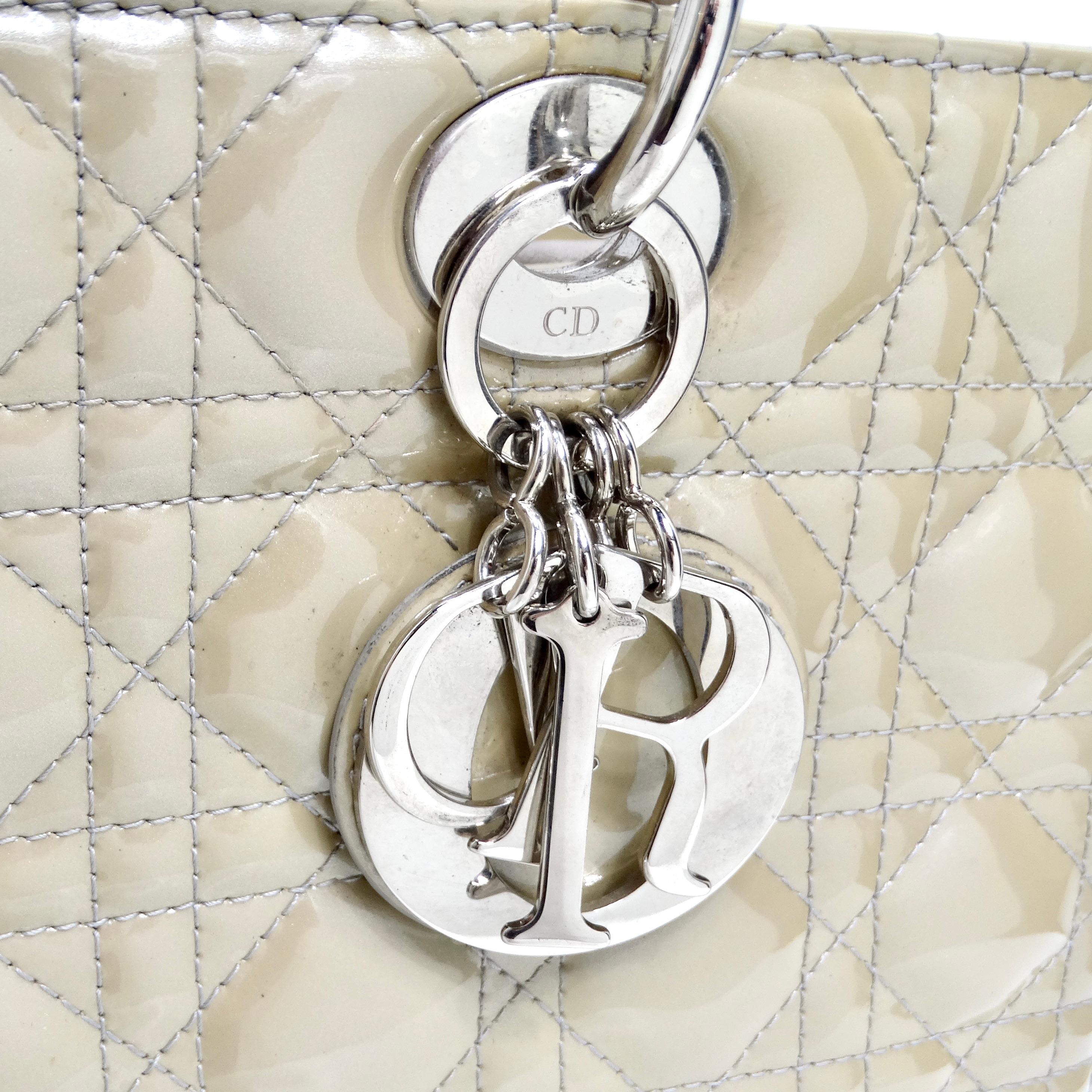 Die Christian Dior Patent Cannage Large Lady Dior in Beige ist eine zeitlose und elegante Tasche, die Raffinesse ausstrahlt.

Diese Tasche aus luxuriösem Lackleder in einem sanften Beigeton ist mit dem für Dior charakteristischen geometrischen,