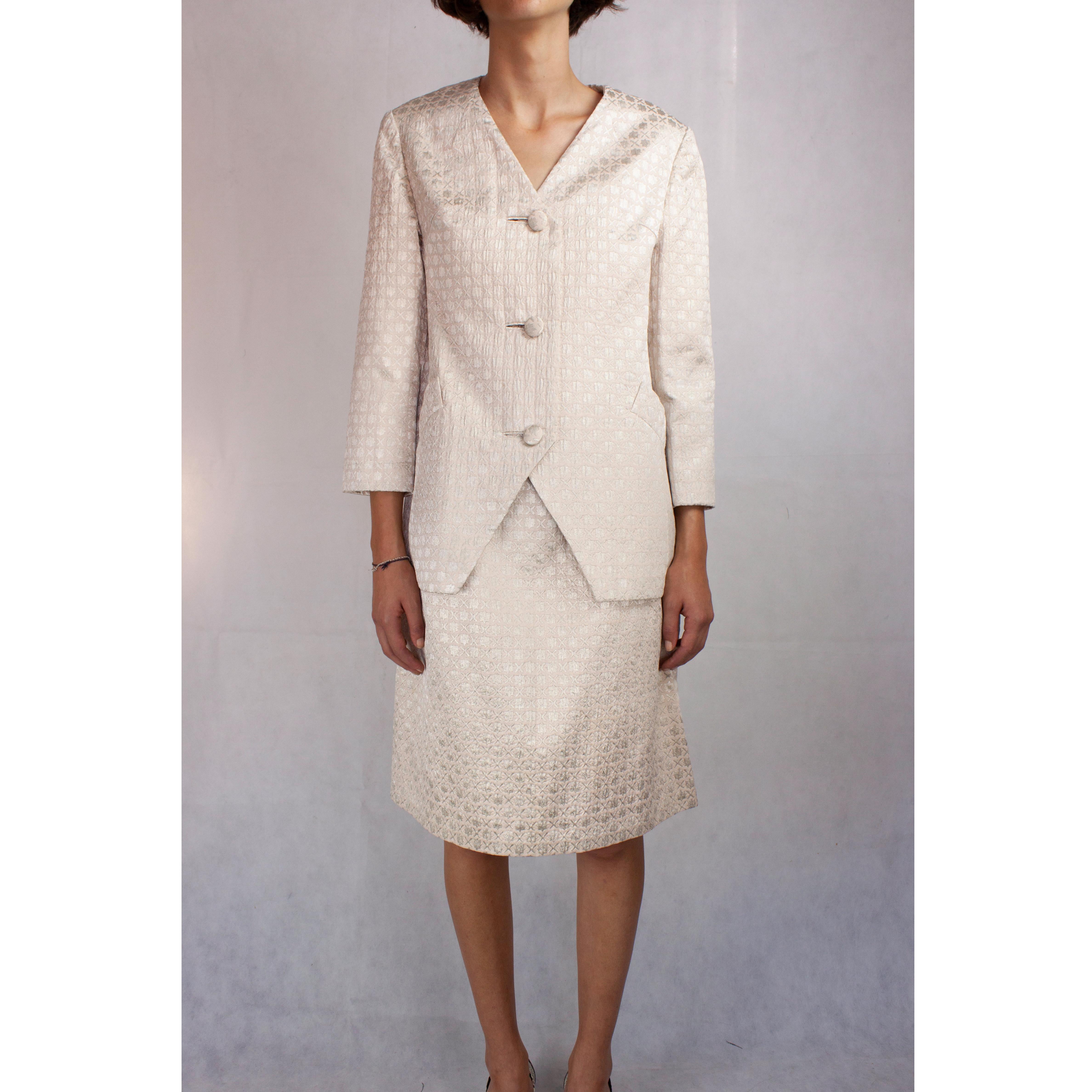 Simplicity and refinement characterize this numbered Christian Dior silk evening skirt ensemble.
The ensemble is tailored to create strong lines but is soften by the luxurious pale pink and silver silk brocade material.
The jacket features a small