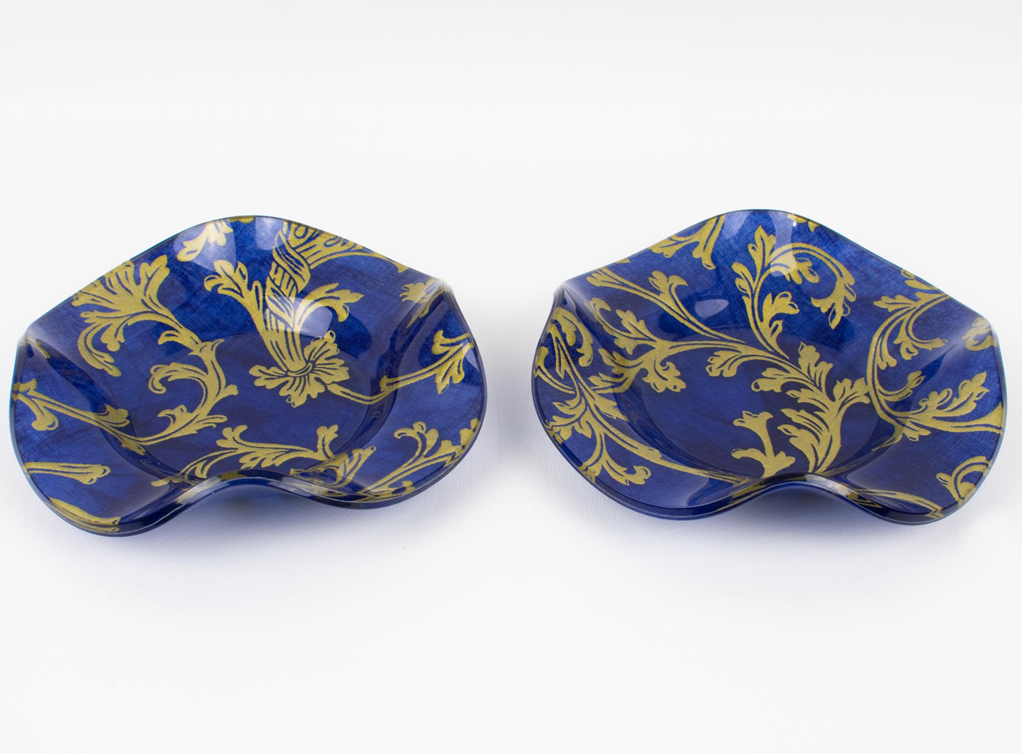 Este romántico set de dos cuencos decorativos, centros de mesa o recogedores fue diseñado para la colección Christian Dior Home. Las piezas presentan una forma redondeada festoneada en Lucite con auténticas Toile de Jouy azul cobalto y doradas