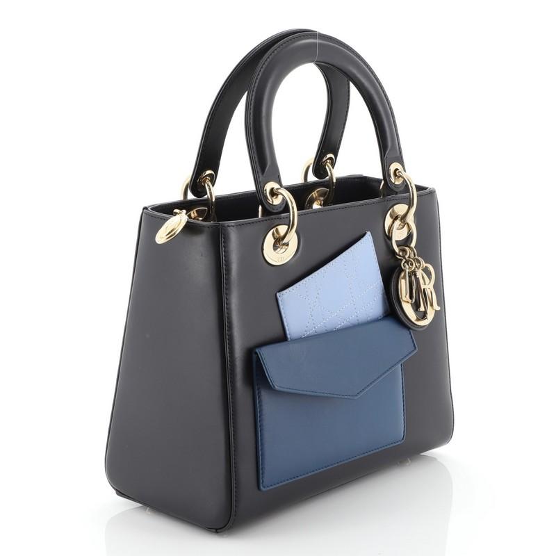 This Christian Dior Pockets Lady Dior Bag Leather Medium, crafted in blue leather, features smooth short dual handles with sleek Dior charms, two front pockets, and gold-tone hardware. The bag's top zip closure opens to a blue leather interior with