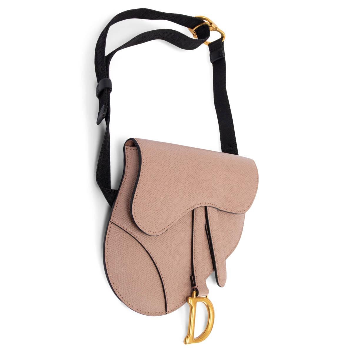 100% authentic Christian Dior Saddle belt pouch in grained powder pink calfskin with gold-tone CD clasp detail on the black nylon logo belt strap. The legendary design features a Saddle flap with a magnetic 'D' stirrup clasp and a back pocket. Lined