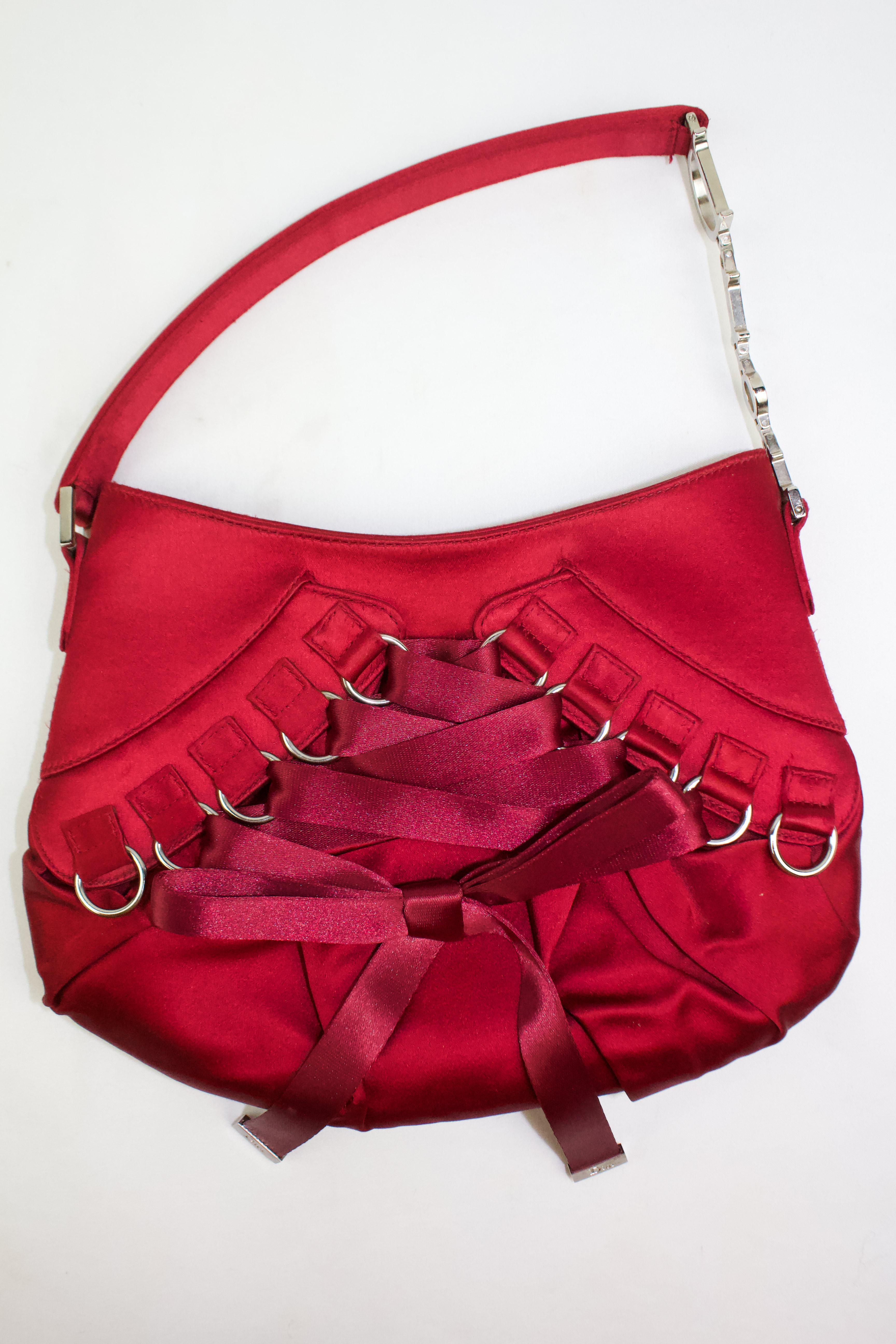 Vintage Christian Dior by John Galliano handbag, 2004. Red silk satin with lace up corset style ribbon. Silver toned hardware with Dior logo letter charms on the strap. 

Condition
Excellent, almost as new. On close inspection, there are some very