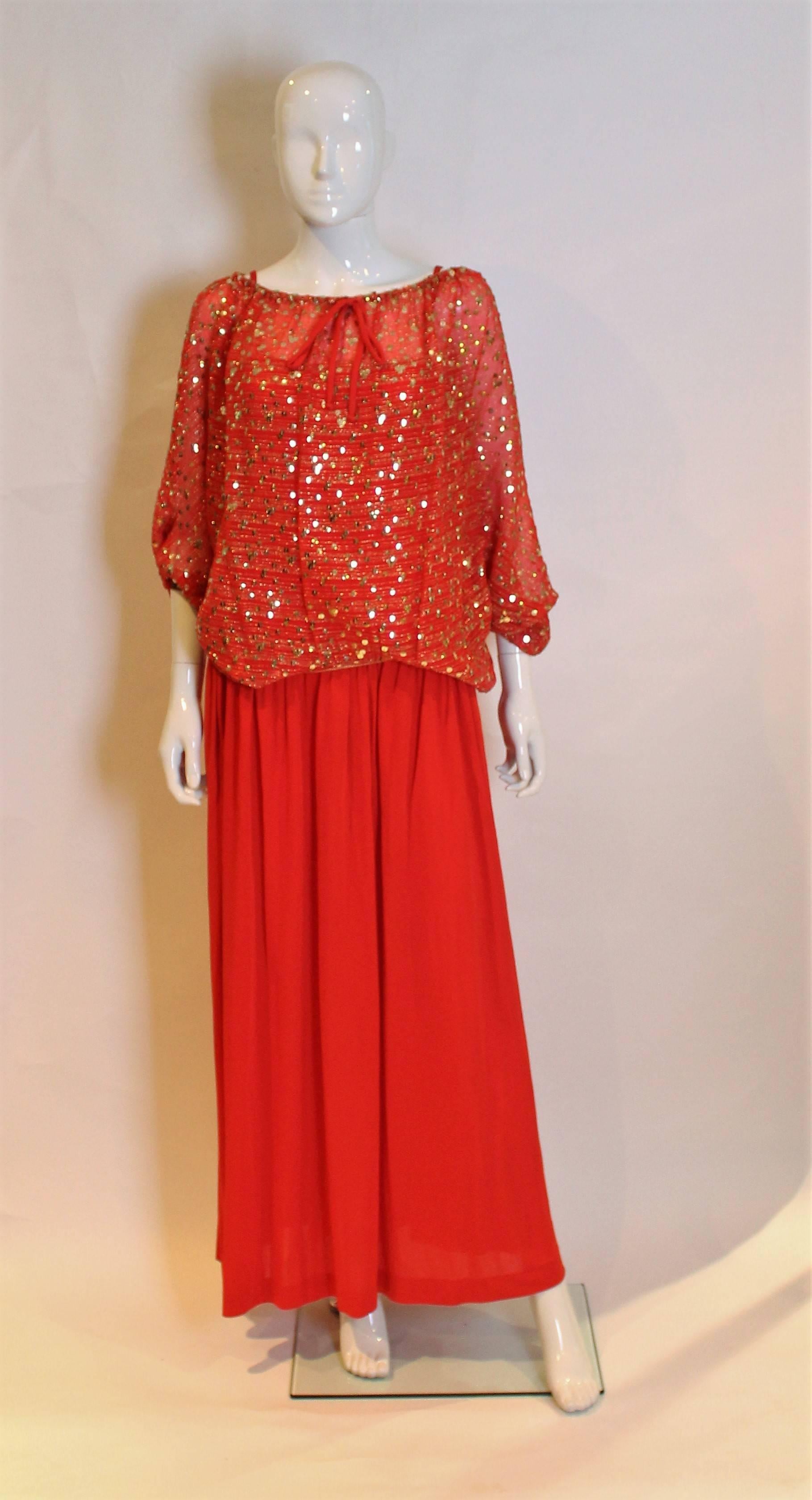 
A lovely evening dress and top by Christian Dior. The red dress has spaghetti straps and a drop waist , with a side zip. The over top is red with gold sequin and thread detail. It has a drawstring waist, elbow length sleaves, and a button opening