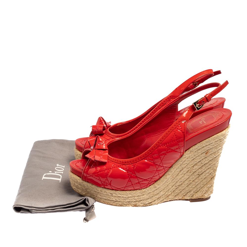 Set on 12 cm espadrille wedge heels, these sandals from the house of Christian Dior feature a red cannage quilted patent leather body with open toes, bow details on the vamps, and buckled slingbacks. They come endowed with comfortable leather