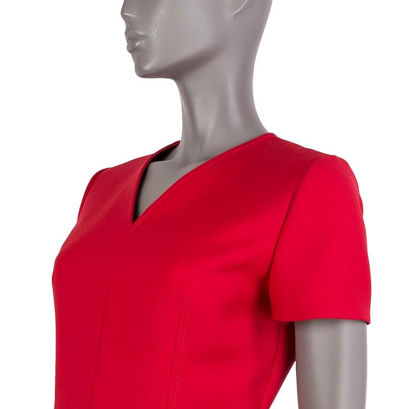 Christian Dior short-sleeve dress in red wool (94%), nylon (4%), and elastane (1%). With v neck, wrap skirt, and one zipper pocket on the side. Closes with invisible zipper on the back and belt-strap with double-D buckle on the side. Lined in red