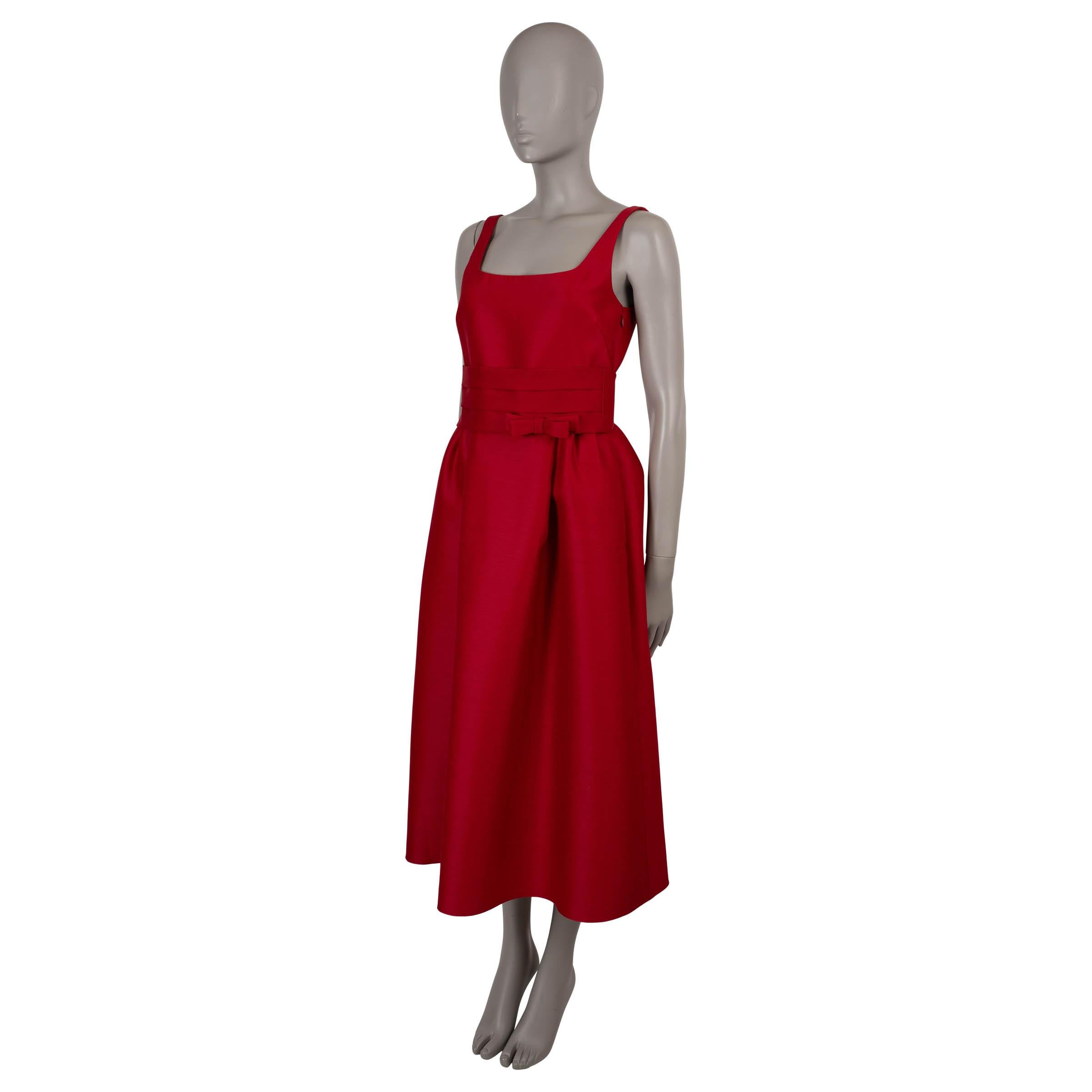Questo abito da cocktail 100% autentico di Christian Dior in lana shantung rossa (84%) e seta (16%) è un mix sorprendente di struttura e femminilità. Con una silhouette senza maniche, fit-and-flare e lunghezza midi, presenta una scollatura a