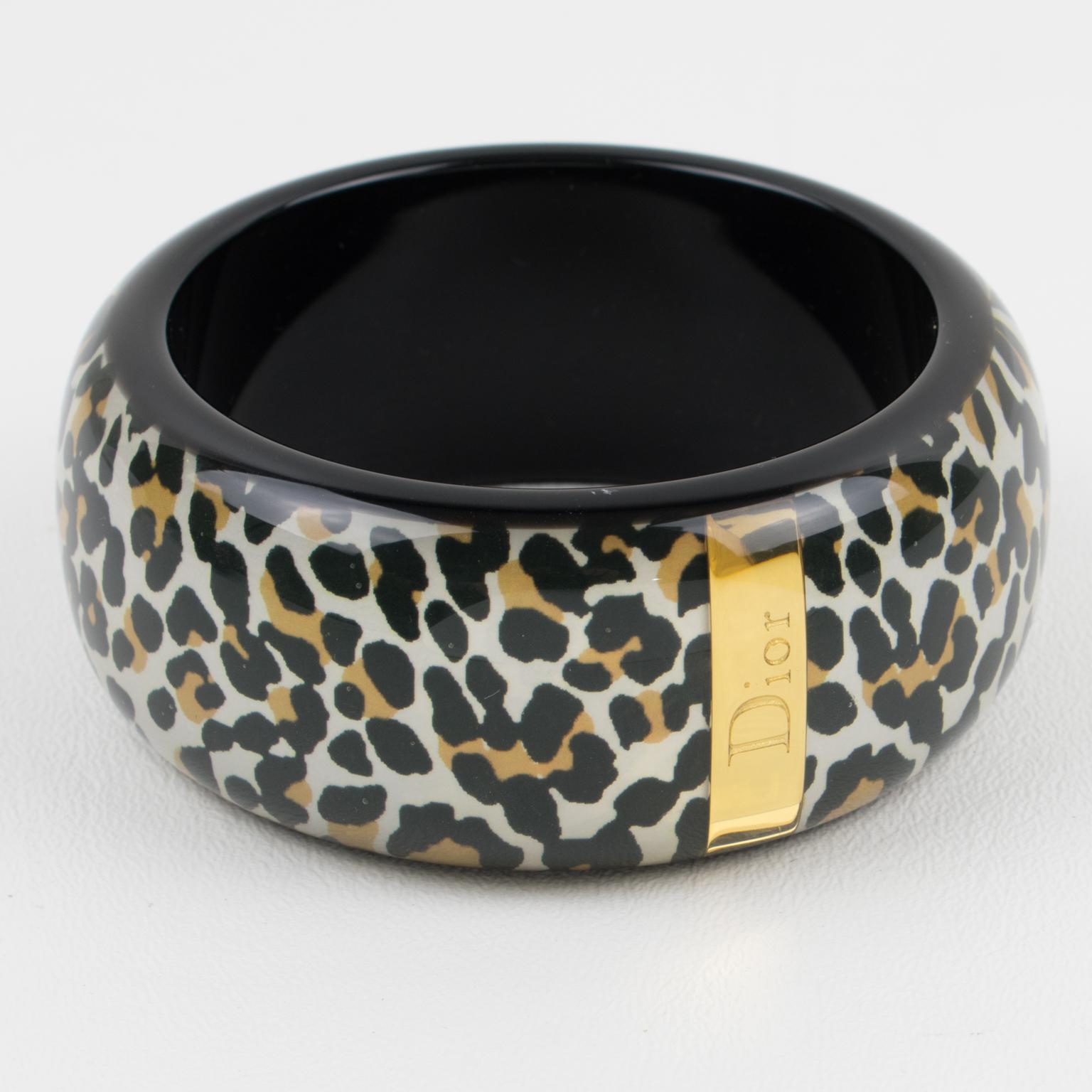 Elegant Christian Dior bracelet bangle. Resin, acrylic, or Lucite bracelet, with a black background and leopard pattern in white, black, and gold colors. Gilded metal stick with 