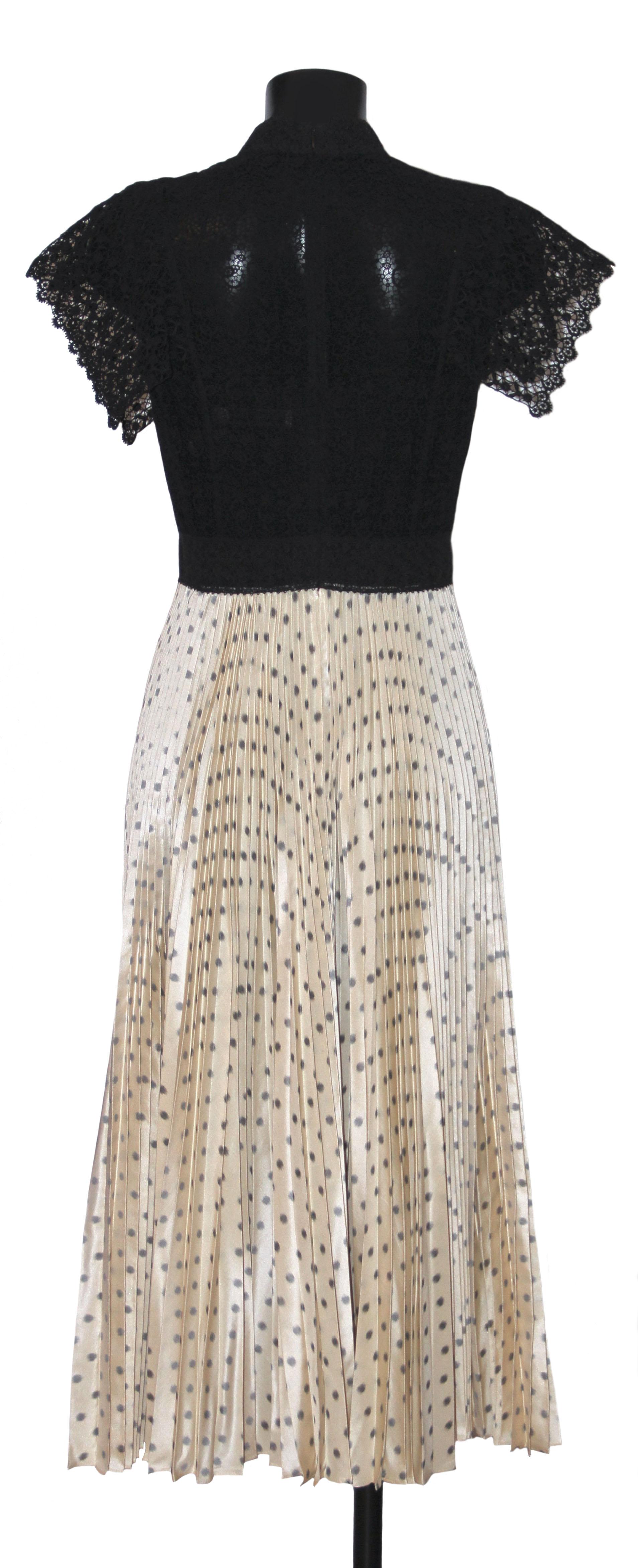 This superb Christian Dior dress is evoking the exceptional craftsmanship of Haute Couture with Polka dots and pleats, favourites of the House.
It features a black cotton intricate knit high-neck top and a full pleated ivory (with black polka dots)
