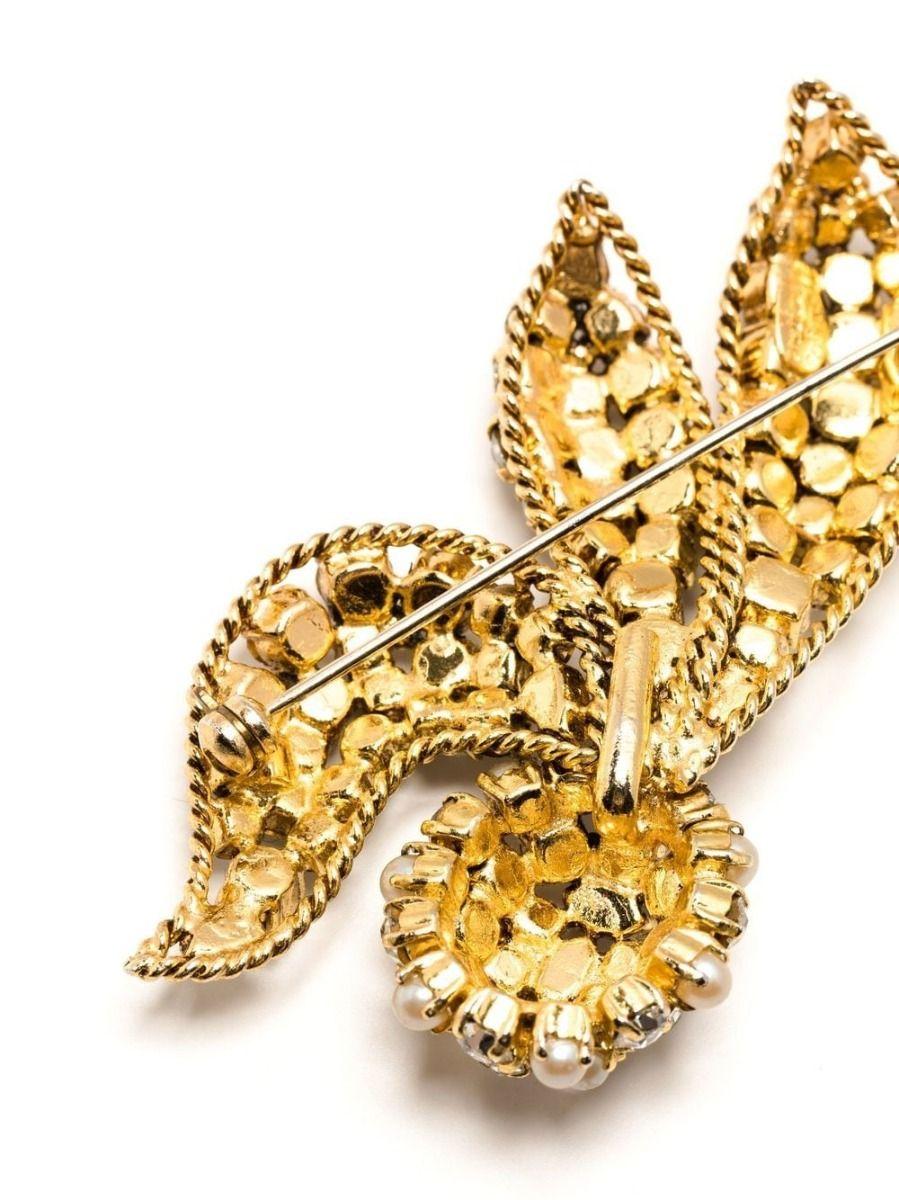 Designed by Grosse for Dior, this vintage brooch displays rows of rhinestones in an abstract shape. Secured using a pin bar fastening, attach to the lapel of your blazer or on your favorite chunky knit sweater. Pair with the matching earrings for