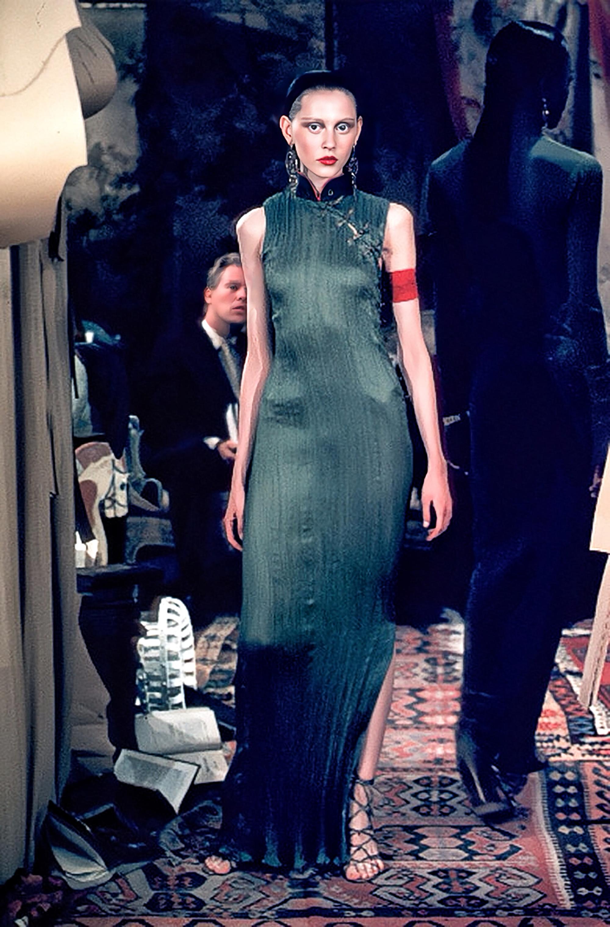 Questo etereo abito a pieghe color avorio della collezione primavera estate 1999 di CHRISTIAN DIOR è caratterizzato da una silhouette fluida e drappeggiata che emana eleganza e disinvoltura. Il corpetto è impreziosito da accenti metallici