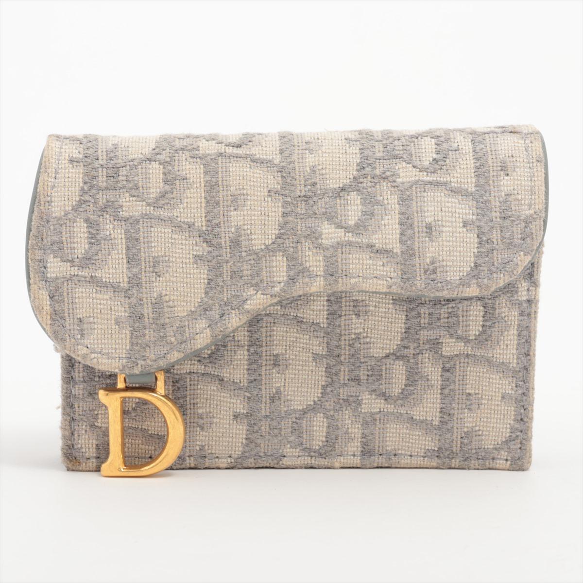 The Christian Dior Saddle Canvas & Leather Card Case in Grey is a sophisticated accessory that seamlessly merges style and practicality. Crafted with meticulous attention to detail, the card case features a combination of durable canvas and supple