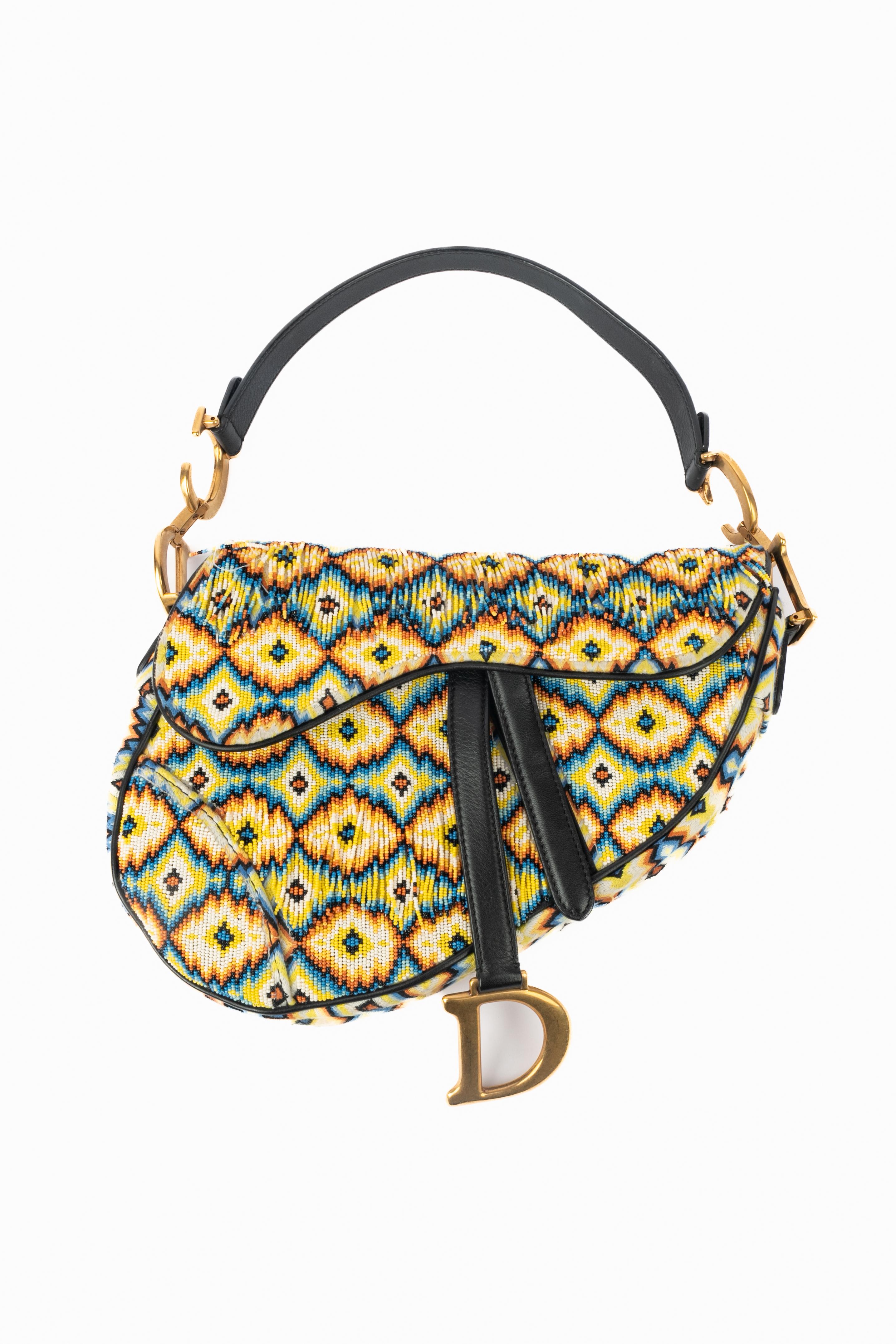 DIOR - (Made in Italy) Borsa 'Saddle' interamente ricamata con un motivo etnico multicolore e impreziosita da perle in tinta. Fodera, manici e chiusura in pelle nera. Elementi metallici dorati. Pezzo con numero di serie e scheda di autenticità.