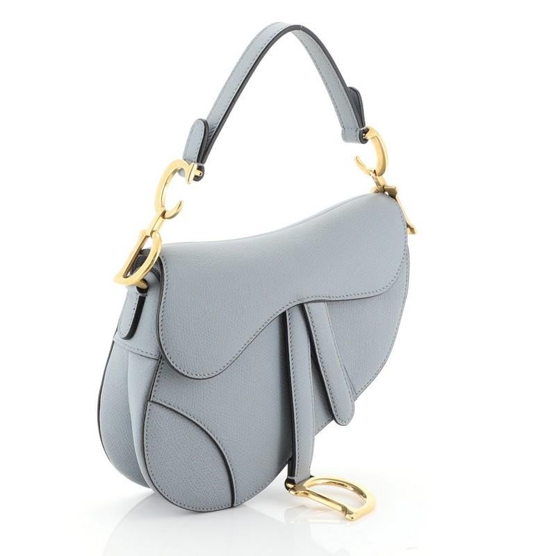 This Christian Dior Saddle Handbag Leather Mini, crafted from blue leather, features a top handle adorned with metal 'CD' hardware and gold-tone hardware. Its fold over top opens to a blue suede interior with zip pocket. 

Estimated Retail Price: