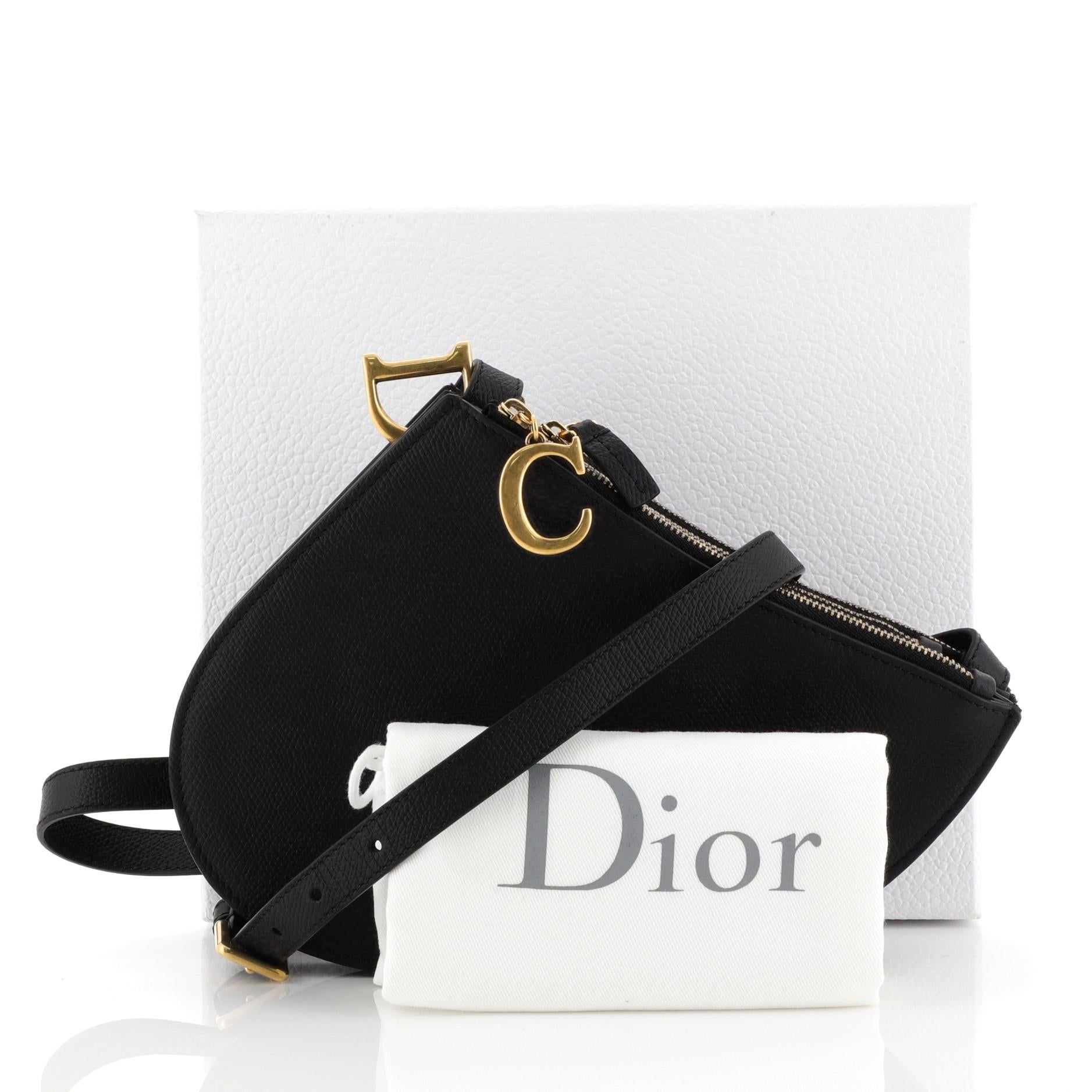 This Christian Dior Saddle Triple Zip Crossbody Clutch Leather, crafted from black leather, features an adjustable leather strap, saddle-shaped silhouette and aged gold-tone hardware. Its three-compartment zip closures opens to a black suede
