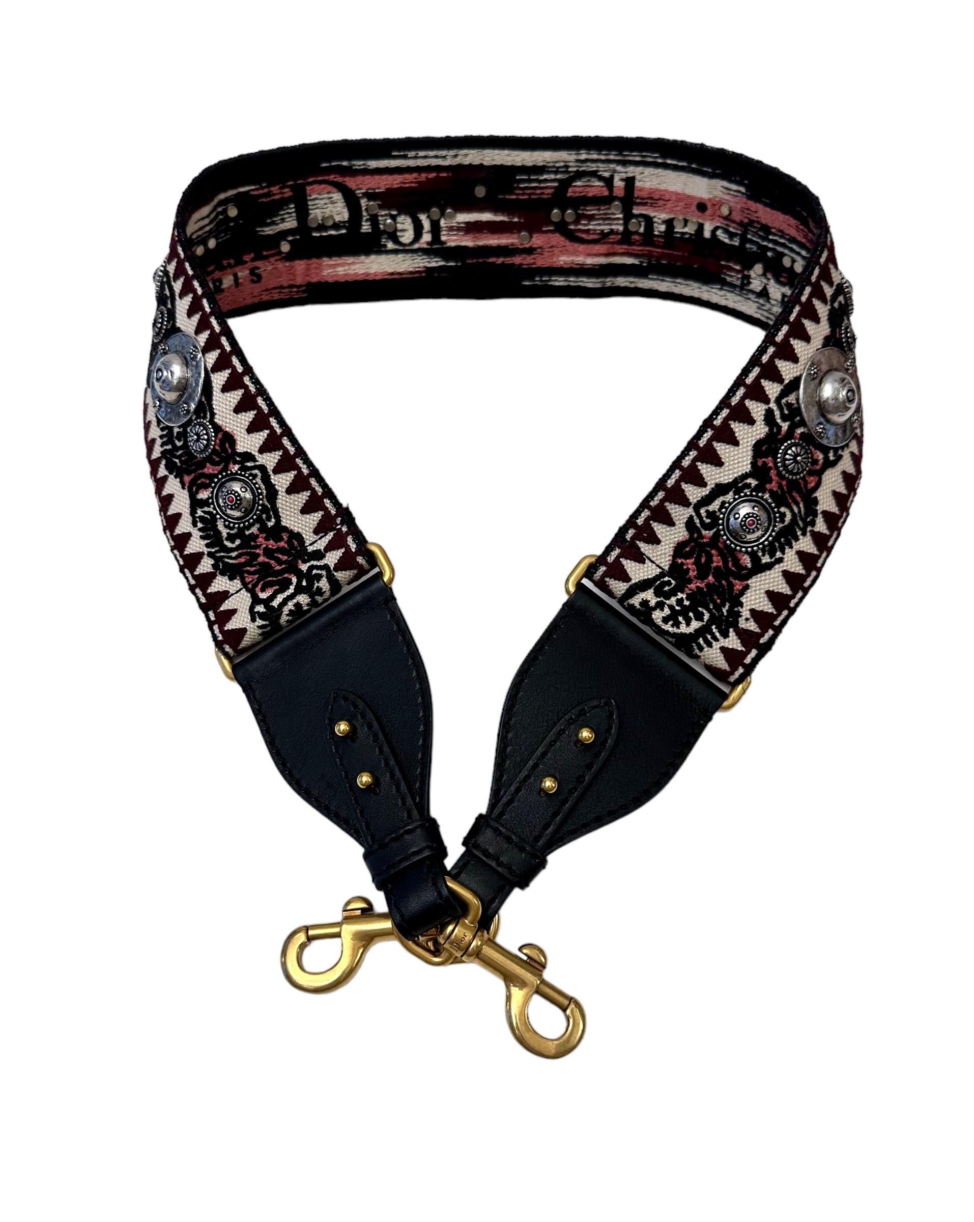The embroidered Dior shoulder strap is a unique accessory that allows the customization of certain House bags. 
This pre-owned one features a graphic design canvas, a mix of embroidery and engraved medallions with a Christian Dior Paris signature at