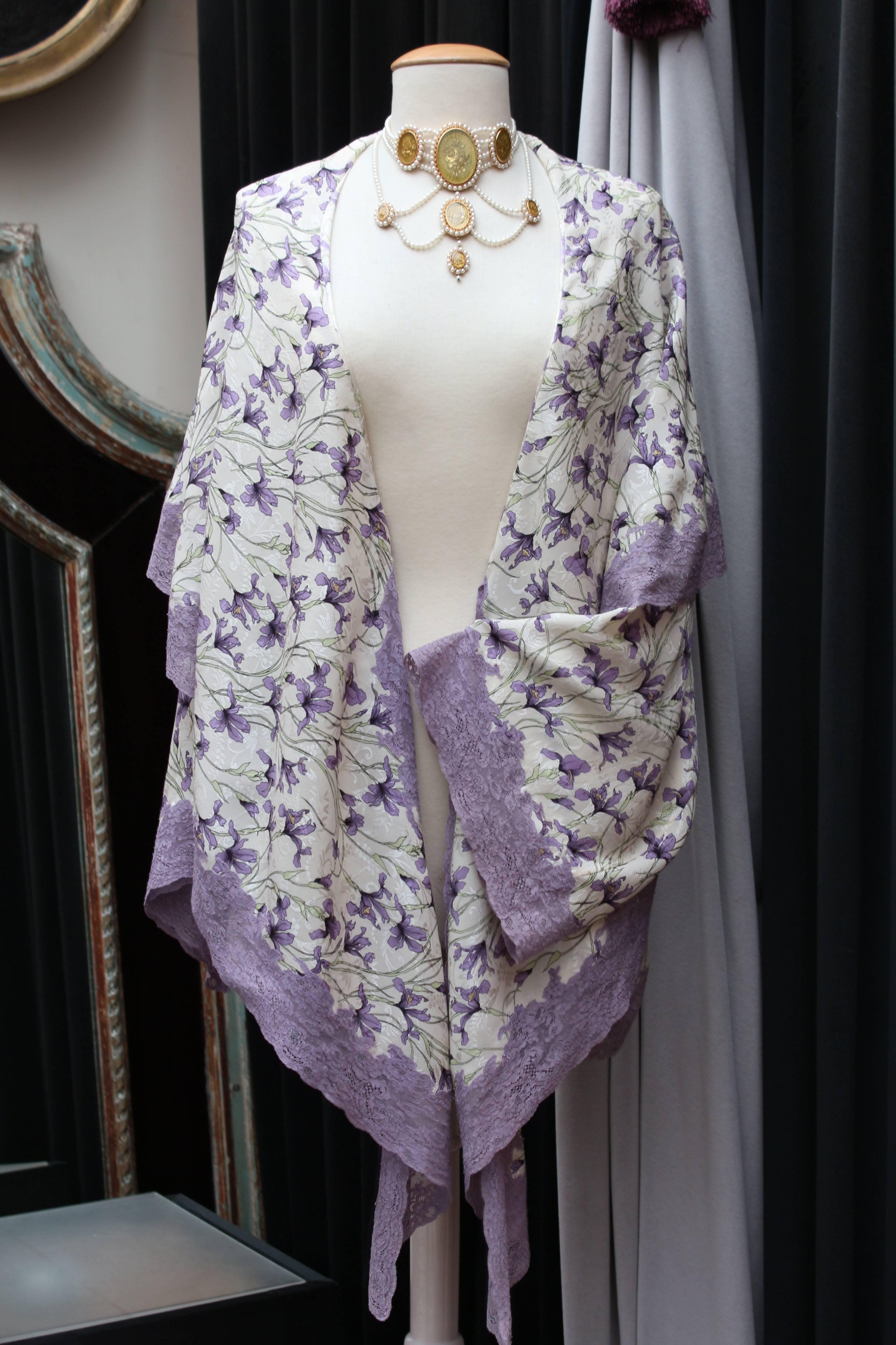 CHRISTIAN DIOR BOUTIQUE PARIS – Loose-fitting jacket in the style of a kimono or a negligee, composed of ivory silk with floral pattern representing lilies, in mauve, purple and almond green colors. The jacket is trimmed with a wide purple lace