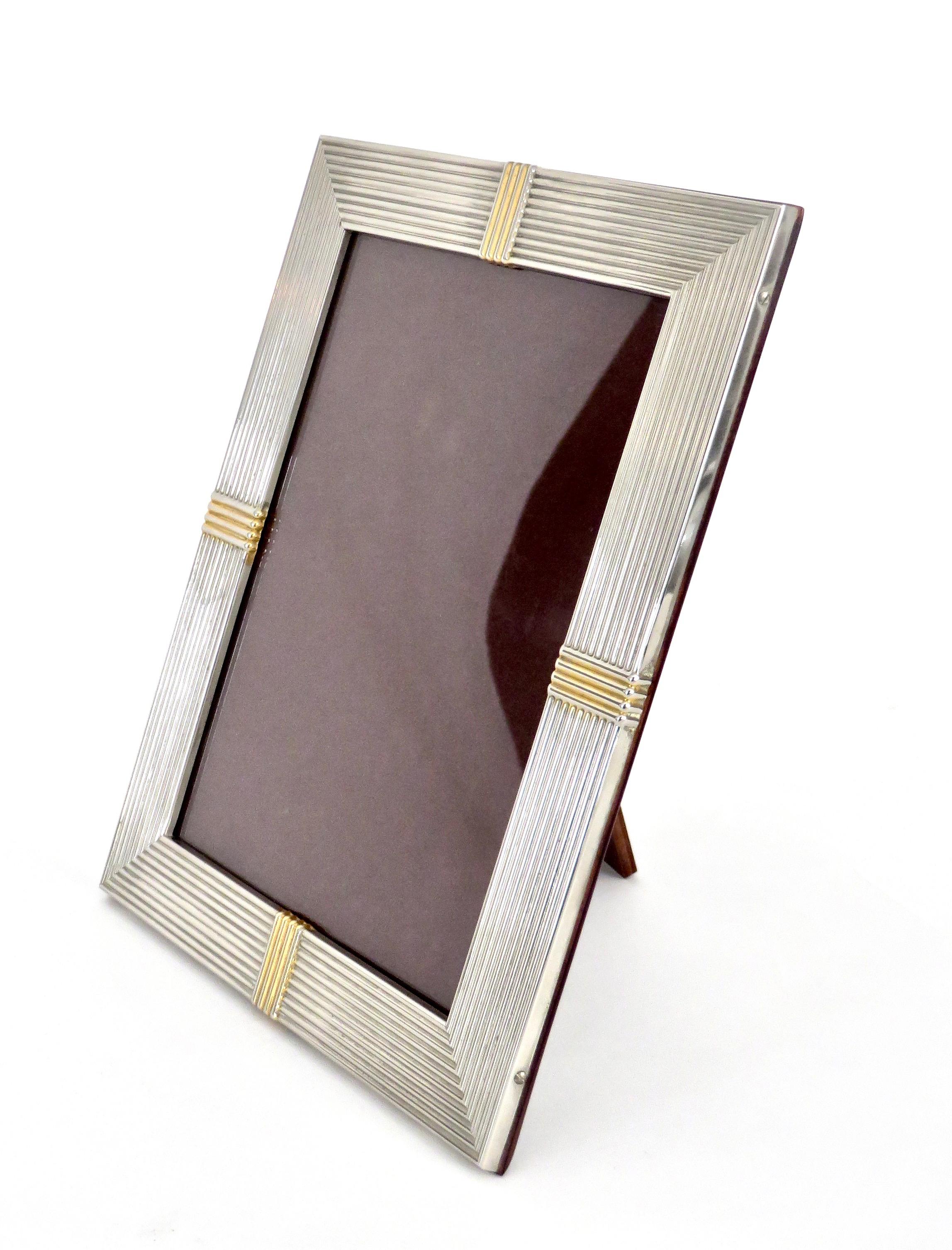 A Christian Dior French silver plate picture frame that is signed Christian Dior.
The decorative motifs are gold washed, circa 1970.
The frame has a mahogany wood back with the Dior signet.
Shown with a larger frame and vide poche.