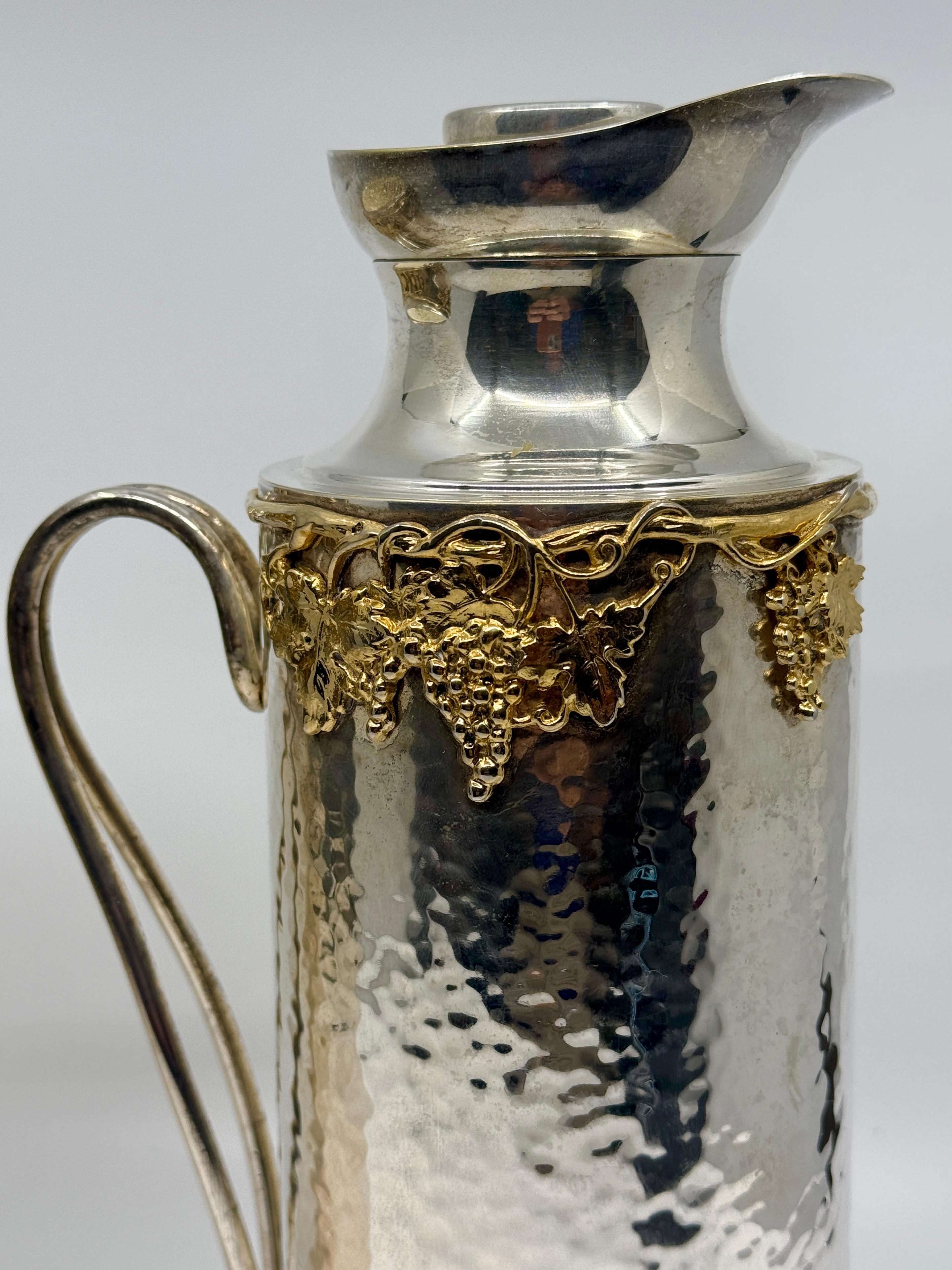 Preciosa pareja de piezas de servicio de Christian Dior en chapa de plata y dorado. Hay un enfriador aislado para botellas de vino y una jarra aislada. Ambas presentan hojas de parra doradas y decoración de uvas alrededor de la parte superior. Están