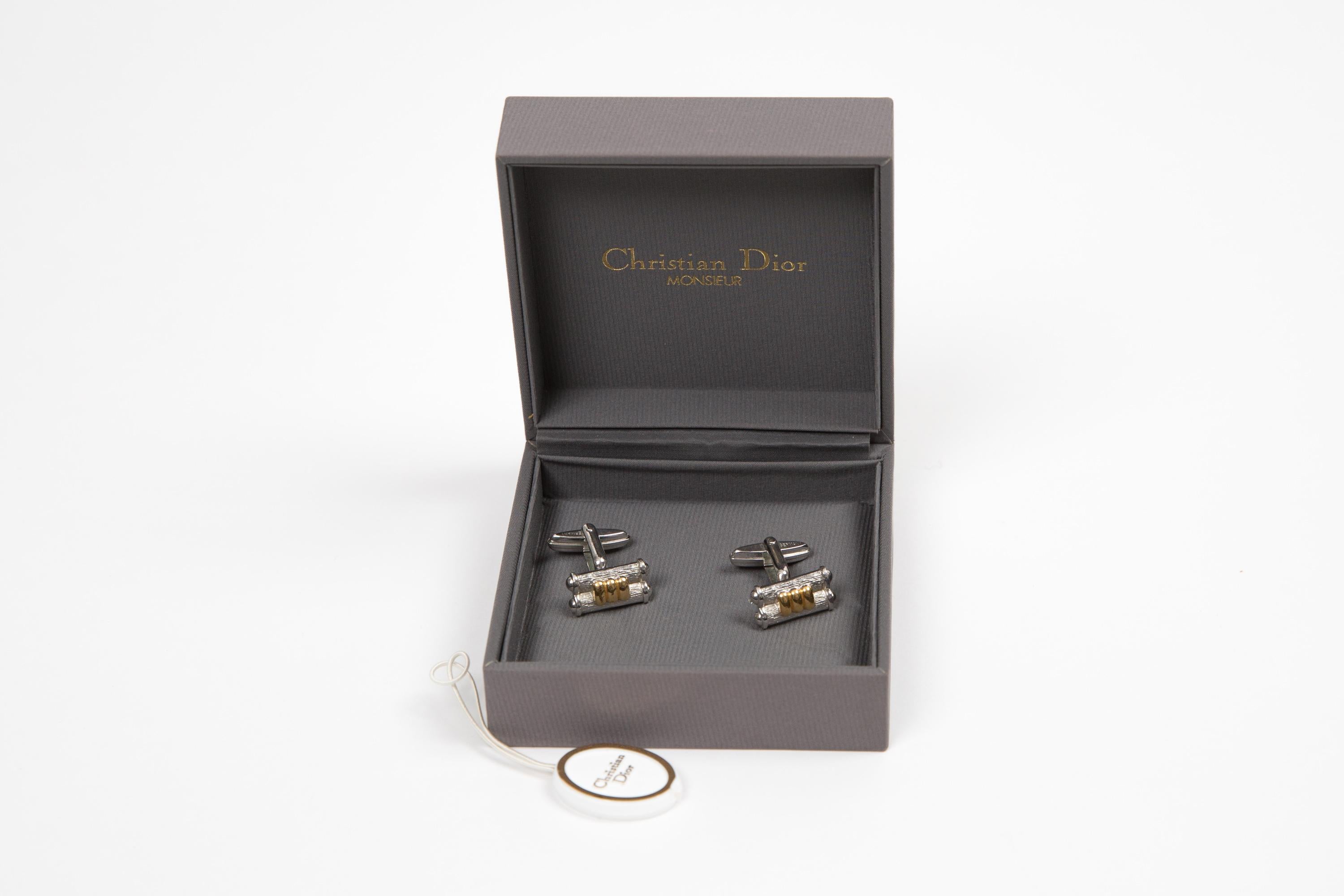 Ensemble de boutons de manchette Christian Dior en métal argenté avec un détail fantaisie en métal doré sur le devant.
Circa 2000s 
En bon état vintage.   
Largeur : 0.39in (1cm)
Longueur Maxi :  0.8in (2cm)
Nous garantissons que vous recevrez cet