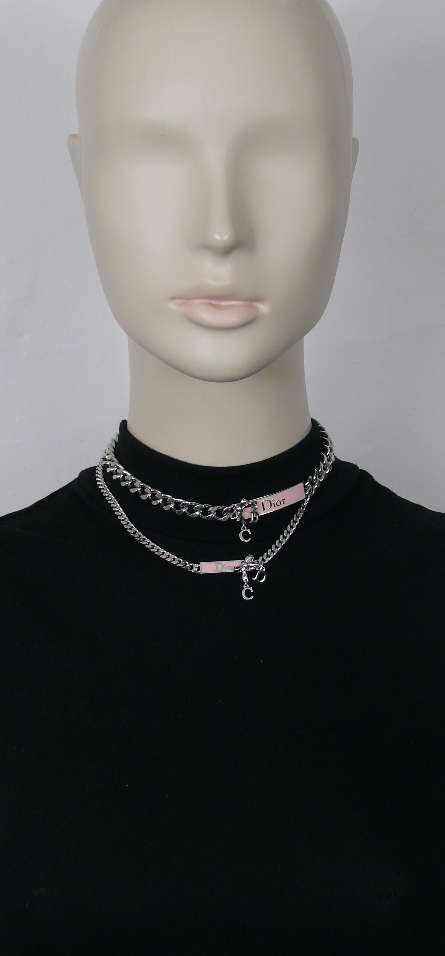 CHRISTIAN DIOR double chain necklace featuring two pink enamel tag withs D I O R, bow and dangling CD initials.

Silver tone metal hardware.

Hook clasp closure.
Adjustable length.

Embossed DIOR.

Indicative measurements : adjustable length from
