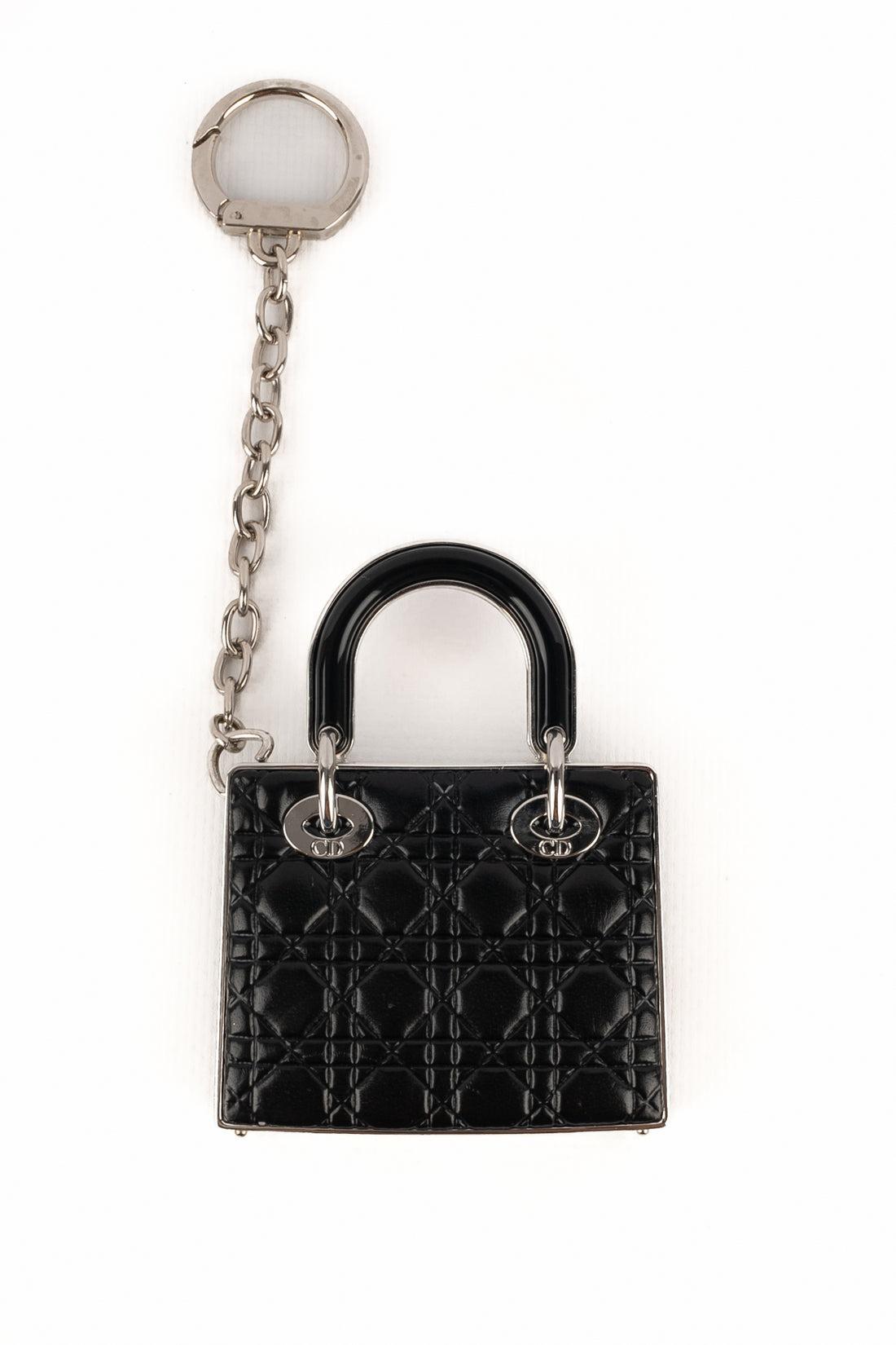 DIOR - (Made in France) Silvery metal bag jewelry representing a black leather quilted Lady Dior bag. The jewelry interior is a makeup palette for face and lips ornamented with a mirror.

Additional information:
Condition: Very good