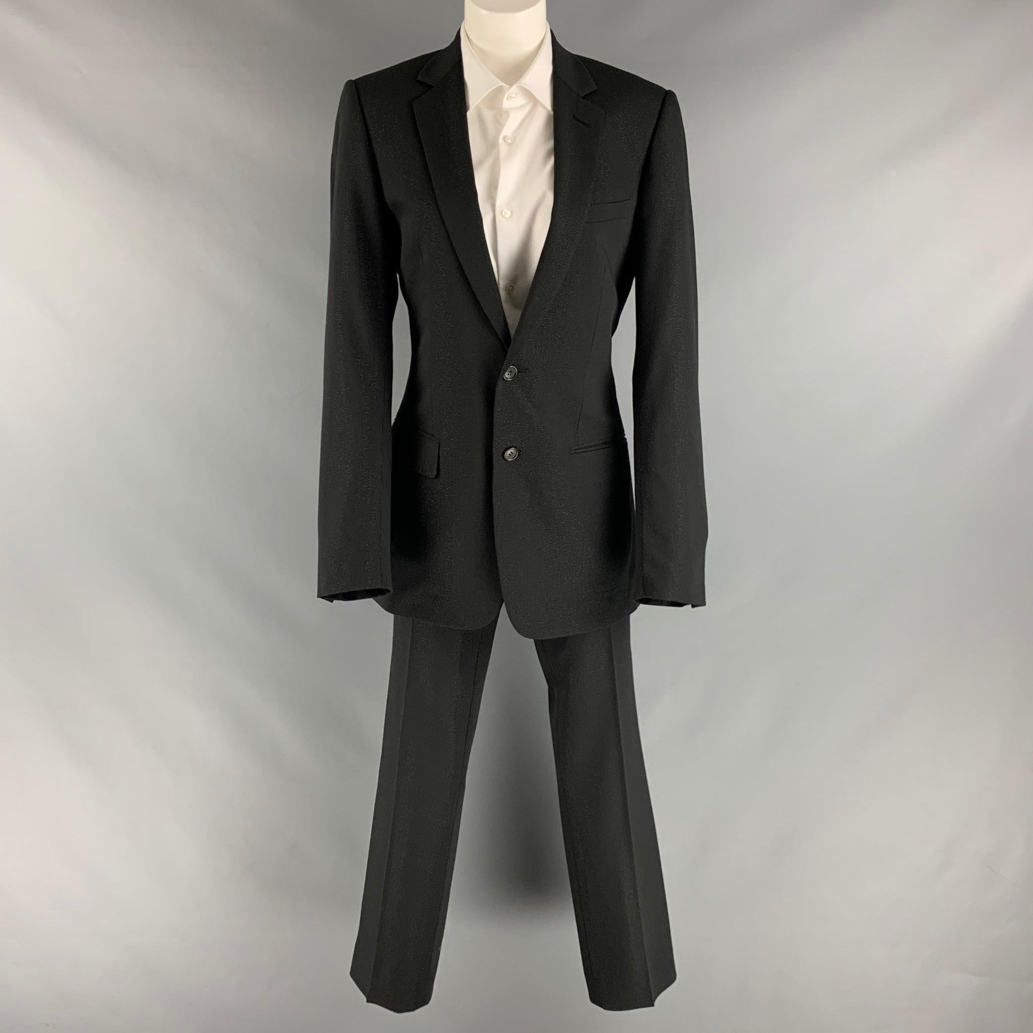 CHRISTIAN DIOR suit comes in a black polyester shimmery woven material with a full liner and includes a single breasted, double button sport coat with a notch lapel and matching flat front trousers.Excellent Pre-Owned Condition. 

Marked:   46