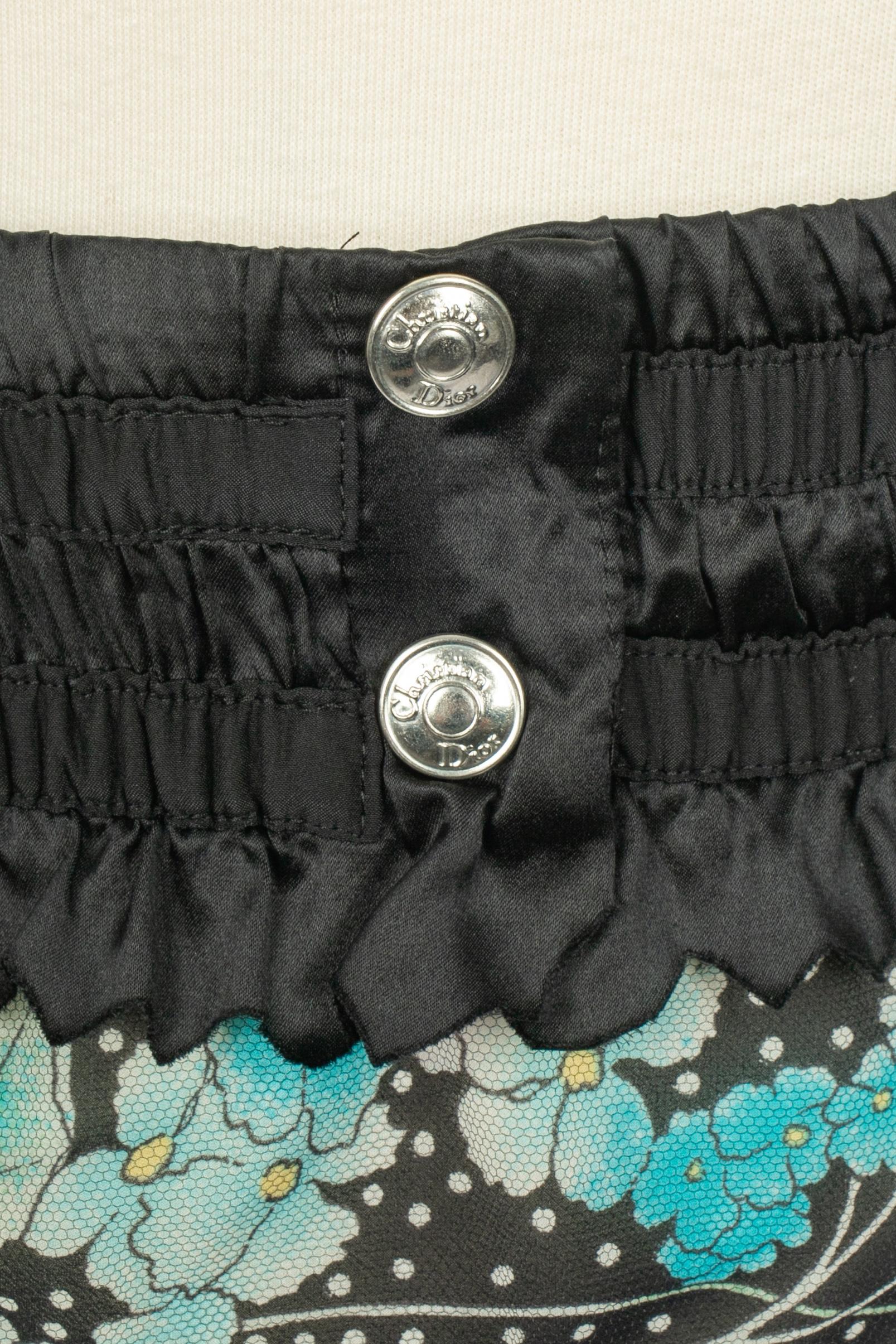 DIOR - (Fabriqué en France) Minijupe en soie avec un motif de fleurs dans les tons bleu et noir, superposé à une longue jupe en tulle noir transparent. Le bas de la jupe est bordé de dentelle blanche. Taille 36FR indiquée. Collection automne-hiver