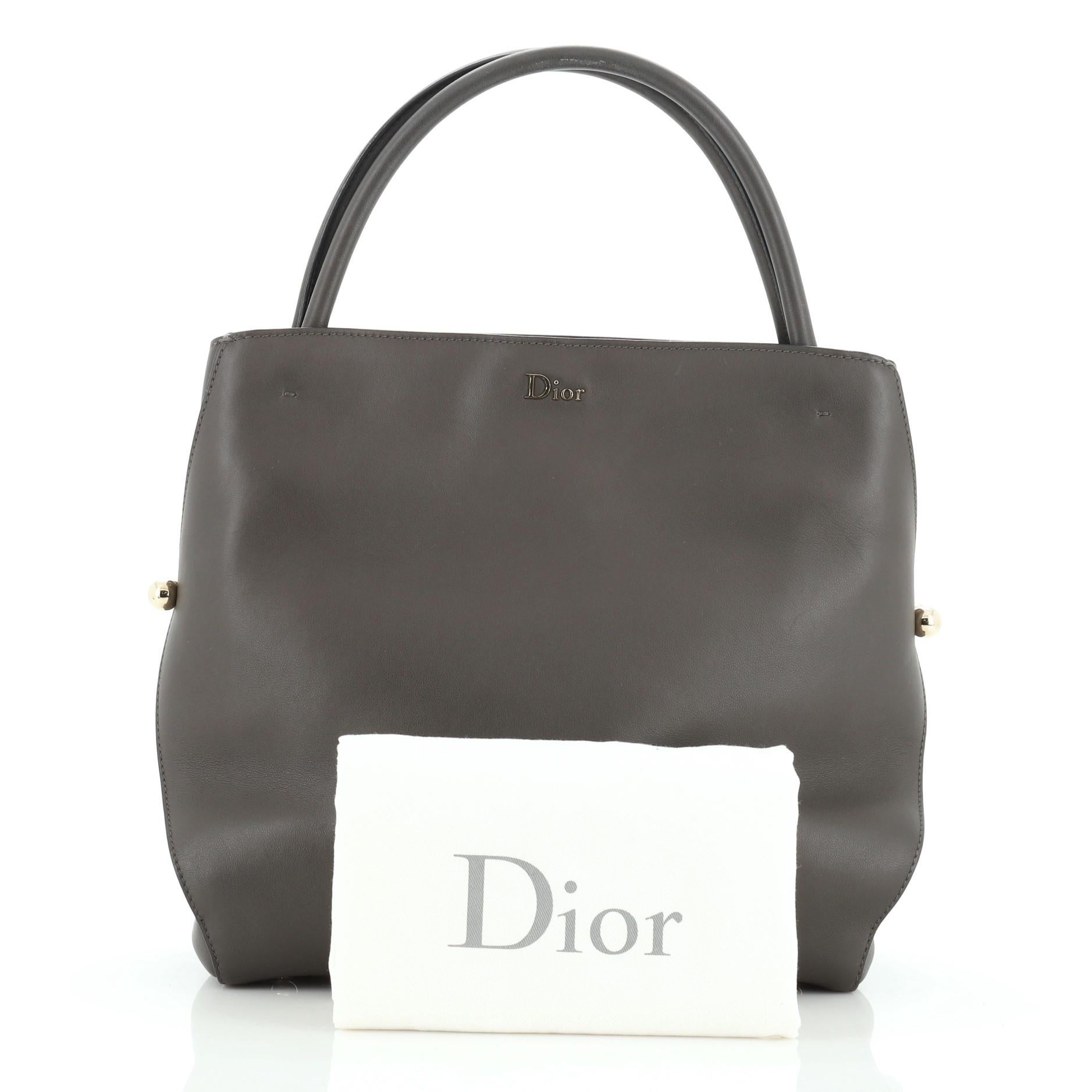 This Christian Dior Top Handle Bar Tote Calfskin Medium, crafted from gray leather, features dual top handles and gold-tone hardware. It opens to a gray leather interior. 

Estimated Retail Price: $4,350
Condition: Very good. Minor scuffs on