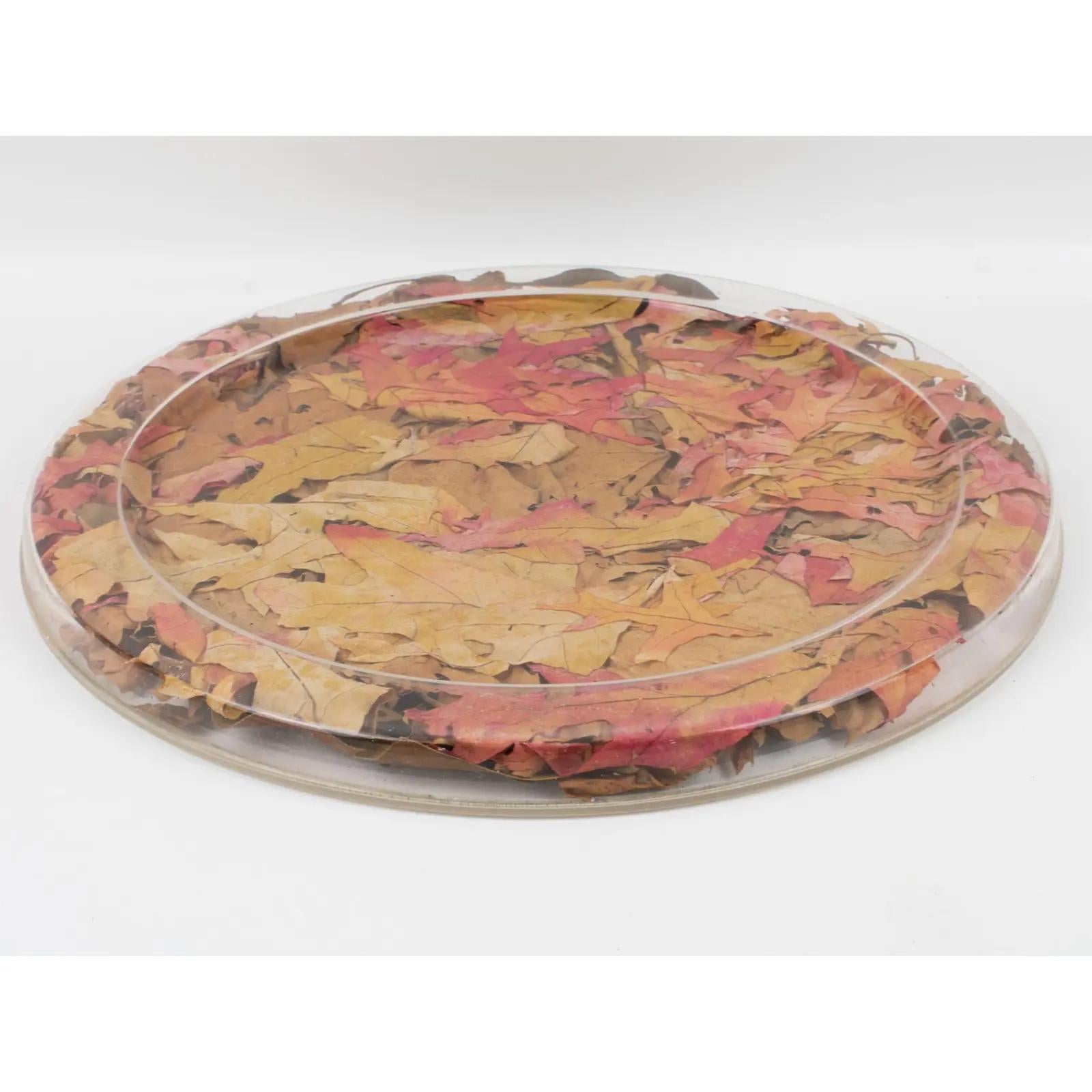 This beautiful serving tray was designed for the Christian Dior Home Collection in the 1970s. This board or platter has a rounded shape and raised edges. With a natural organic touch, it is made of Lucite or plexiglass with dried autumn maple leaves