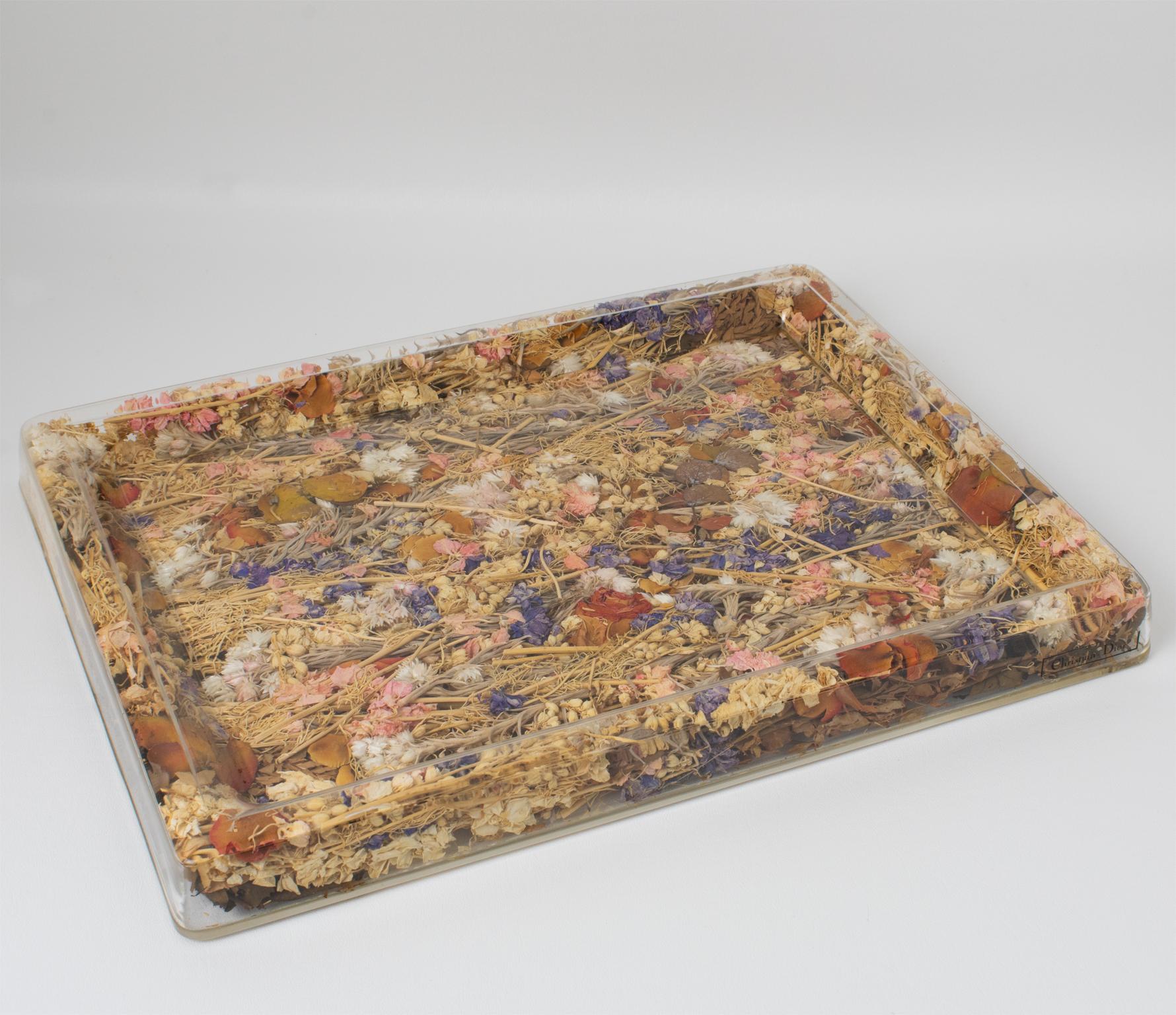 This special serving tray is a Christian Dior design from the 1970s Home Collection. This board or platter has a rectangular shape with raised edges. This barware or serveware accessory is of clear Lucite or plexiglass with genuine multicolor dried