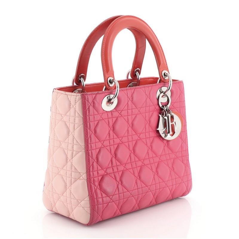 This Christian Dior Tricolor Lady Dior Handbag Cannage Quilt Leather Medium, crafted in orange and pink cannage quilted leather, features short dual handles with Dior charms and silver-tone hardware. Its top zip closure opens to an orange leather