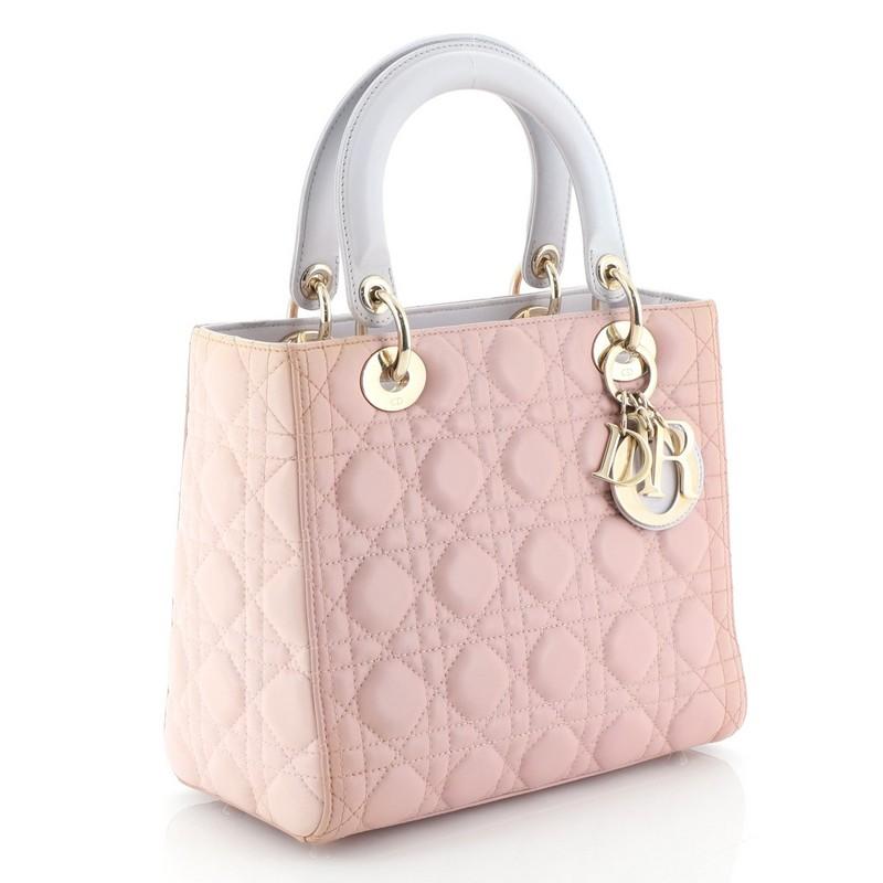 This Christian Dior Tricolor Lady Dior Handbag Cannage Quilt Leather Medium, crafted in pink and purple cannage quilted leather, features short dual handles with Dior charms and gold-tone hardware. Its top zip closure opens to a purple leather