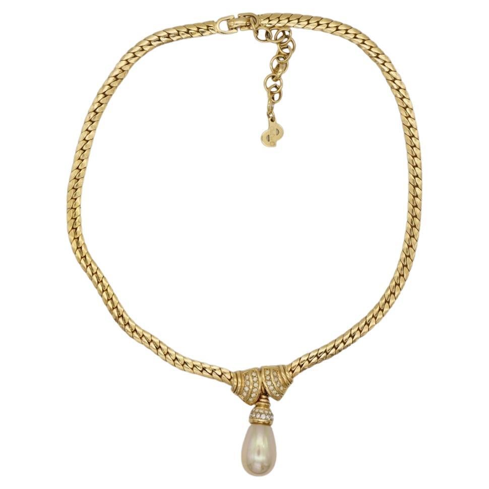 Very excellent condition. 100% Genuine.

Constructed from polished gold plated brass with a snake chain design, this Christian Dior necklace is adorned with a Swarovski crystal-embellished bow and a faux pearl-embellished pendant.

Marked 'Chr.Dior