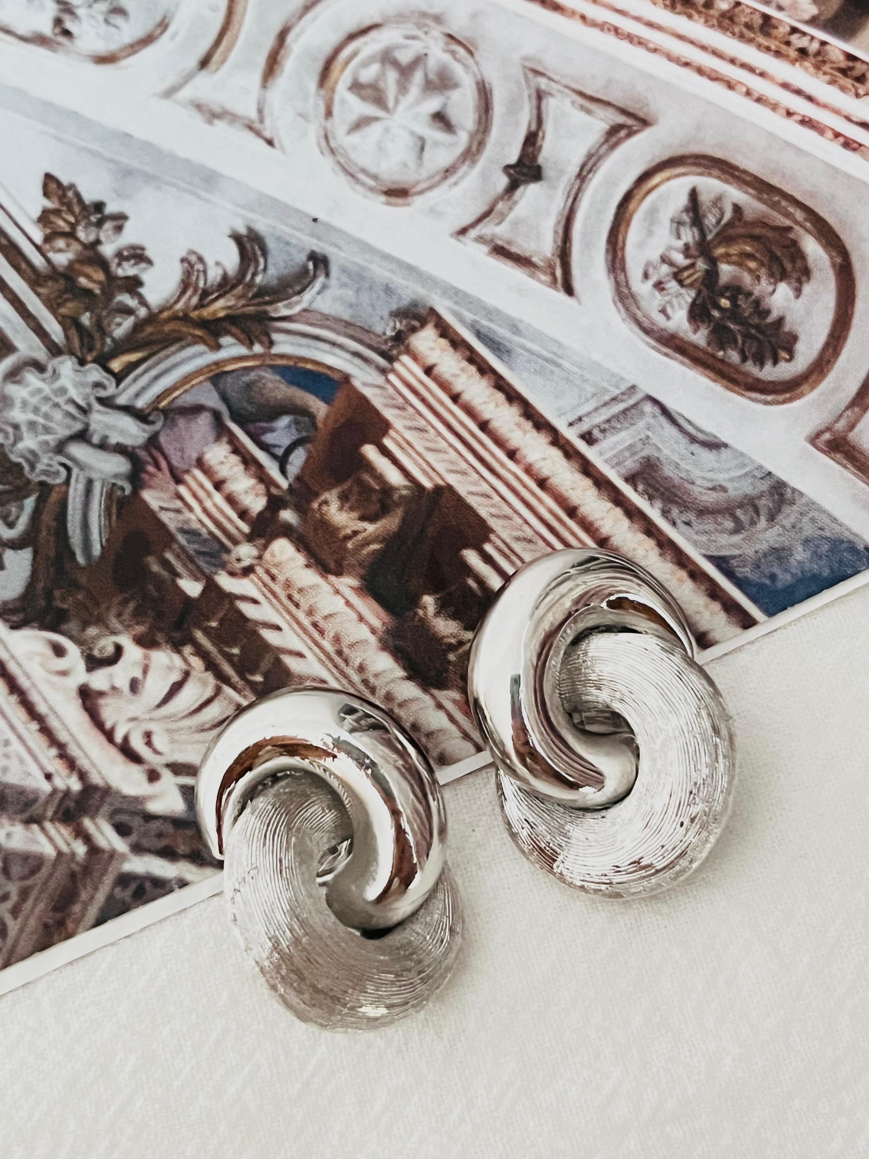 Christian Dior Vintage 1980s Unisex Glow Matte Interlocked Knot Twist Hoop Chunky Clip Earrings, Silver Tone

Very excellent condition. 100% Genuine.

A very beautiful pair of earrings by Chr. DIOR, signed at the back.

Size: 3.0*2.1 cm.

Weight: