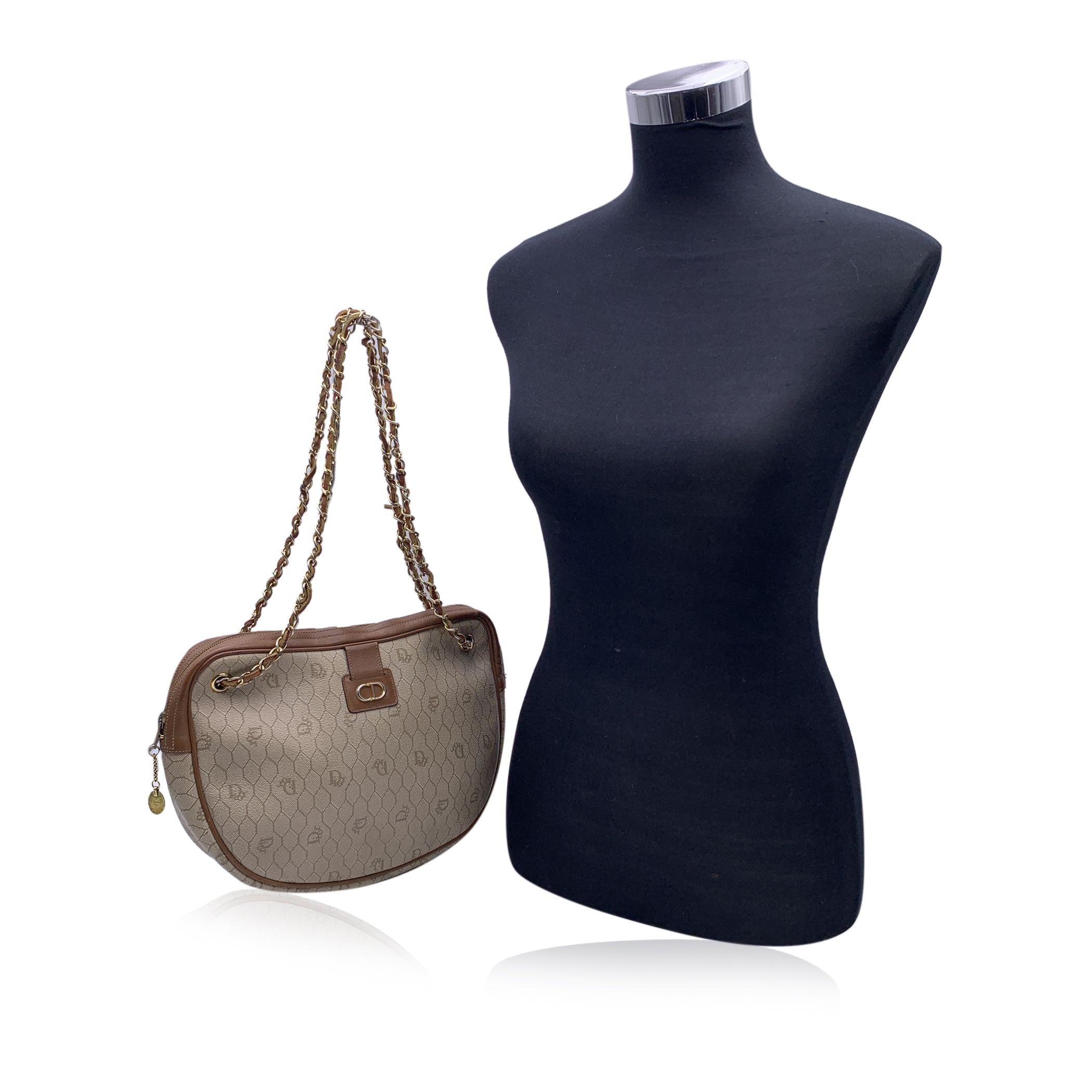 Vintage Christian Dior beige logo canvas shoulder bag with brown leather trim. Gold metal CD logo on the front. Upper zipper closure. Gold metal interwoven leather shoulder strap. 'CHRISTIAN DIOR Paris - Made in France' tag inside. Condition B -