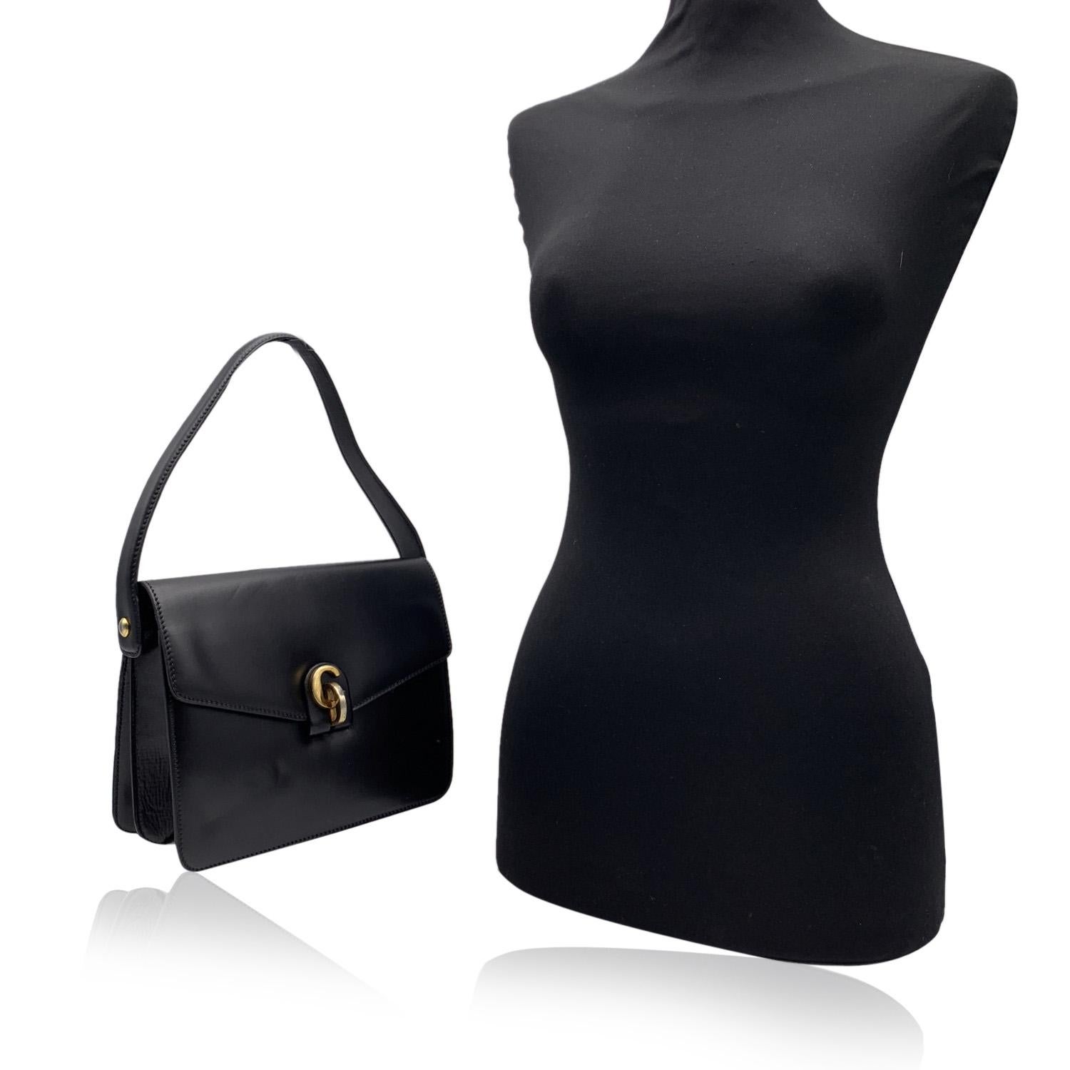 CHRISTIAN DIOR Vintage-Handtasche aus schwarzem Leder. Die Tasche hat einen kurzen Schulterriemen, ein goldfarbenes, CD-förmiges Detail auf der Vorderseite und einen Knopfverschluss. Innenfutter aus schwarzem Wildleder. 2 Hauptfächer mit 1