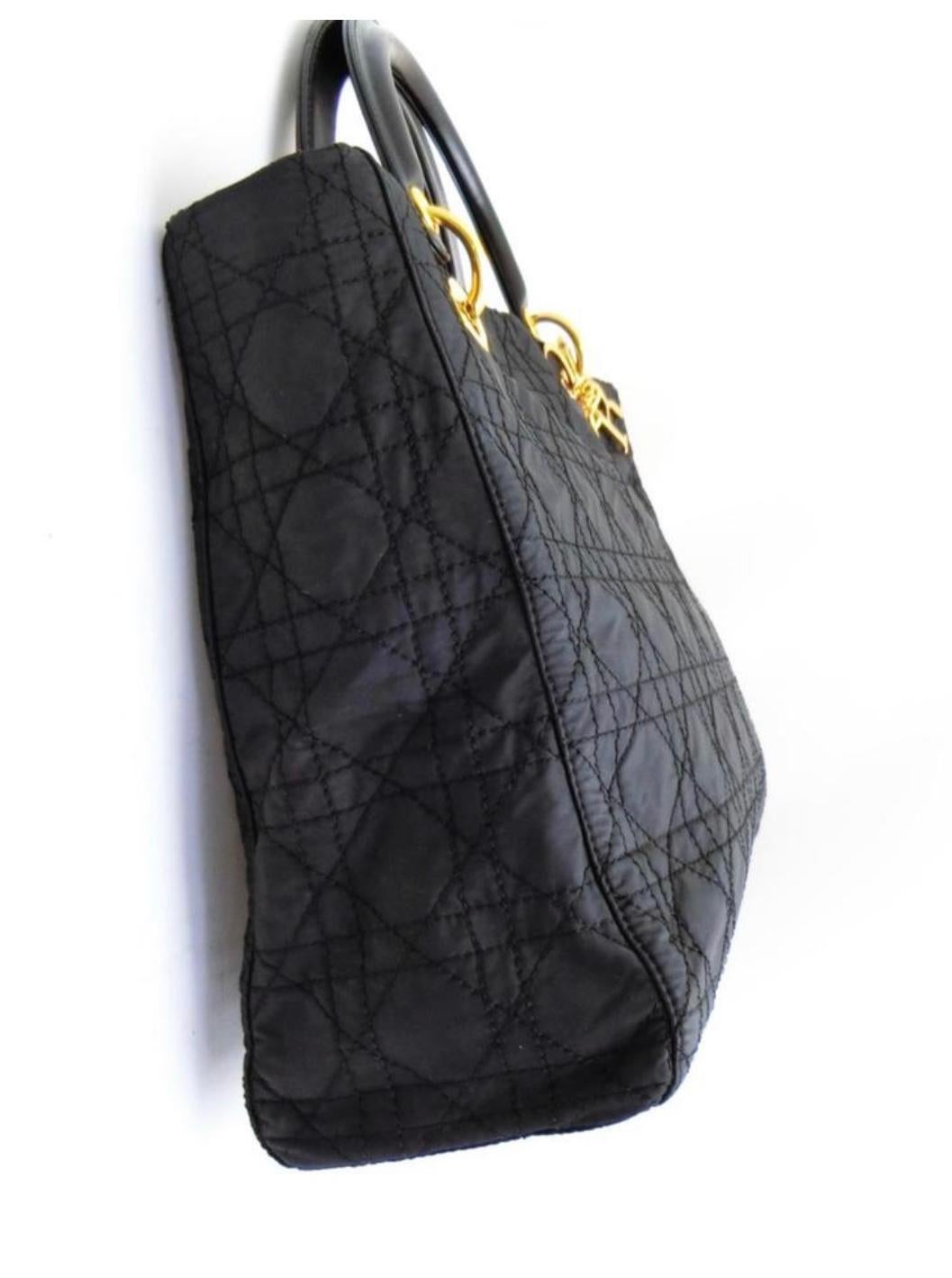 This authentic Christian Dior Cannage  Lady Dior bag is exquisitely crafted with quilted black nylon and stunning gold-tone hardware. Perfect for a night on the town or dinner party, it is sized perfectly to carry 