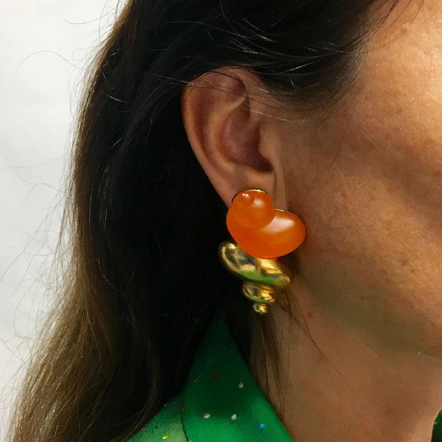 Ear clips in the shape of golden metal snails and orange resin. Perfect condition. Made by Robert Goossens, for the launch of a perfume.
Length: 5.5 cm, width: 3 cm. 
Very good condition.
Delivered in a non original pouch.