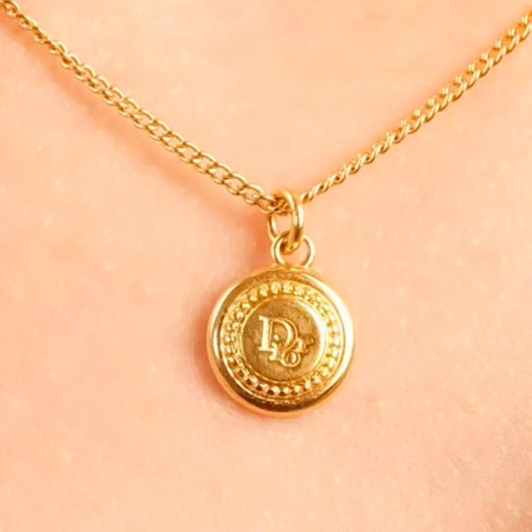 Vintage Christian Dior gold plated fine chain necklace with small coin 'Dior' logo pendant.

Condition Details: In very good, gently used condition consistent with its age and use. There are very light scratches and wear to the metal; however, it