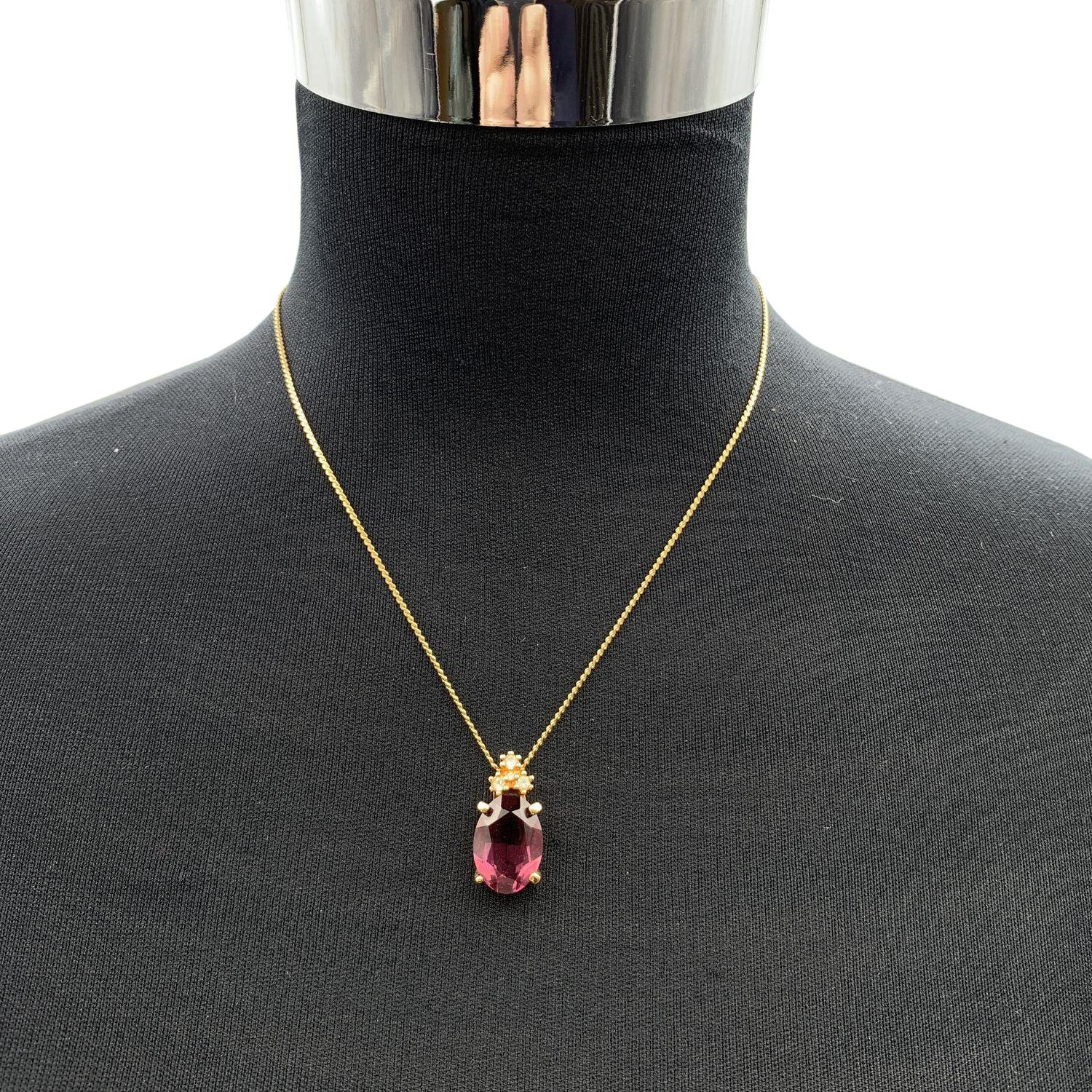 Collier vintage Christian Dior en chaîne de métal doré avec un cristal ovale violet suspendu par 3 petits strass blancs. Fermeture par anneau à ressort. Petite breloque CD à l'extrémité du collier. Longueur de la chaîne : environ 16.5 inches - 41.8
